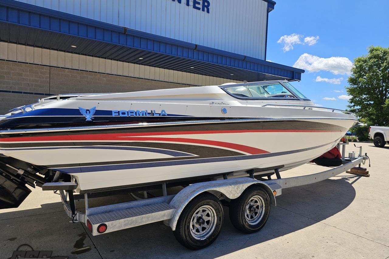 2005 Formula 271 FASTech boat on trailer, parked outdoors under clear sky.