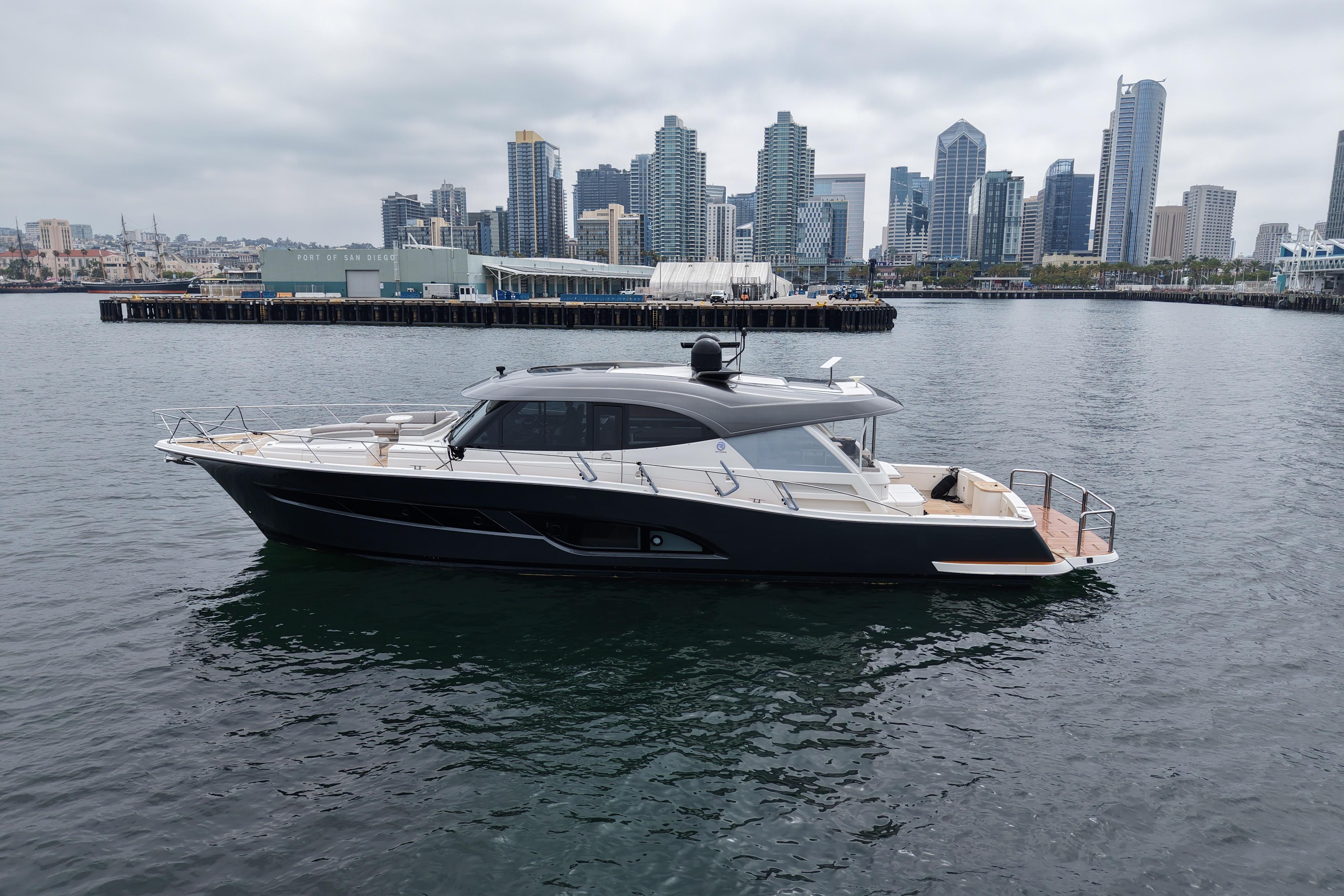 2023 Riviera 645 SUV yacht cruising in San Diego harbor with city skyline backdrop.