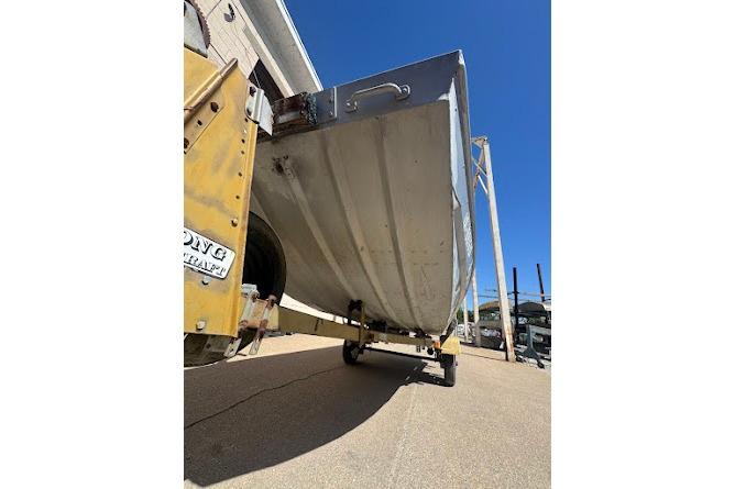 1973 Monark 14 Jon boat on trailer, viewed from below, outdoors.