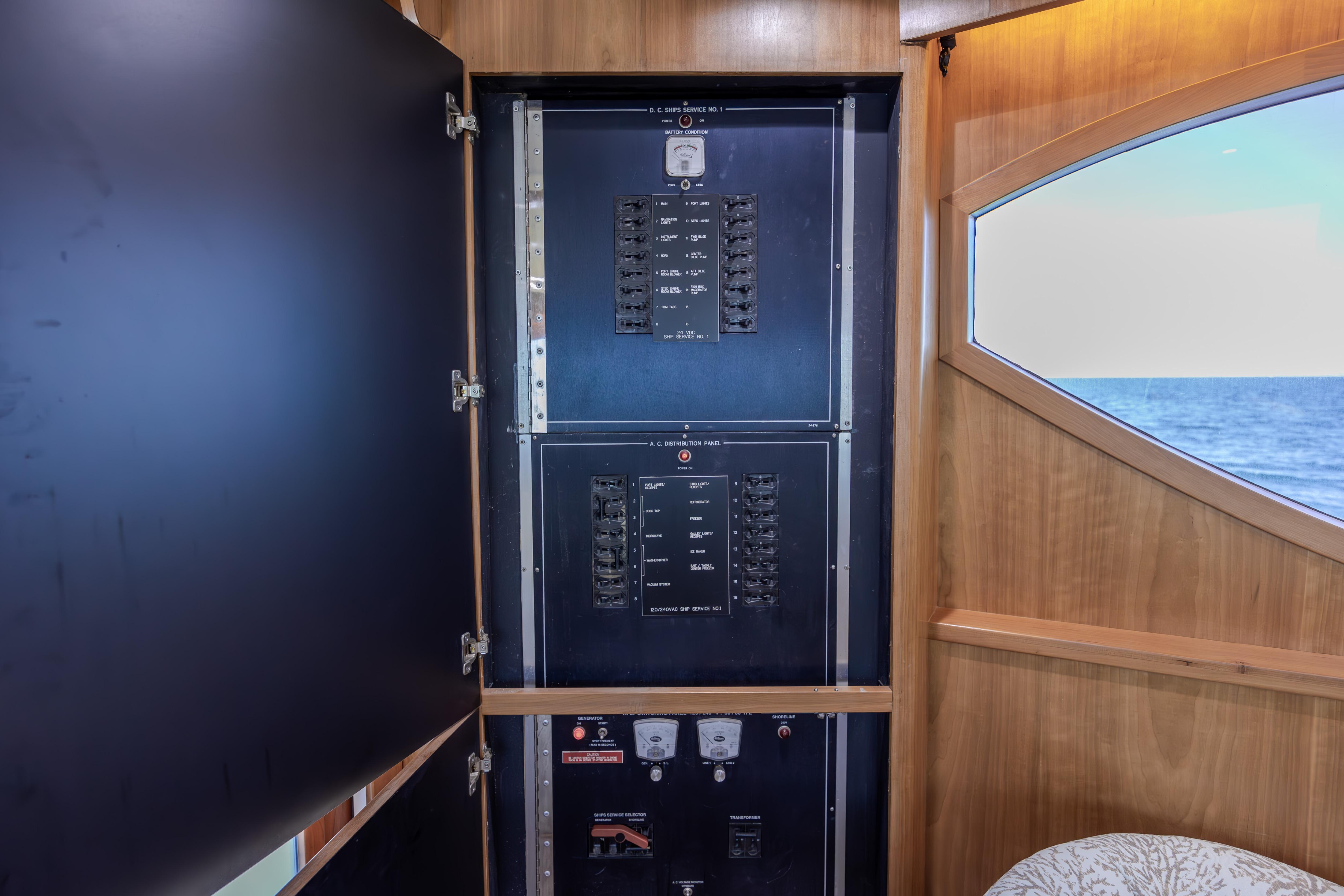 Electrical panel inside 2000 Hatteras 50 Convertible yacht, with ocean view through window.
