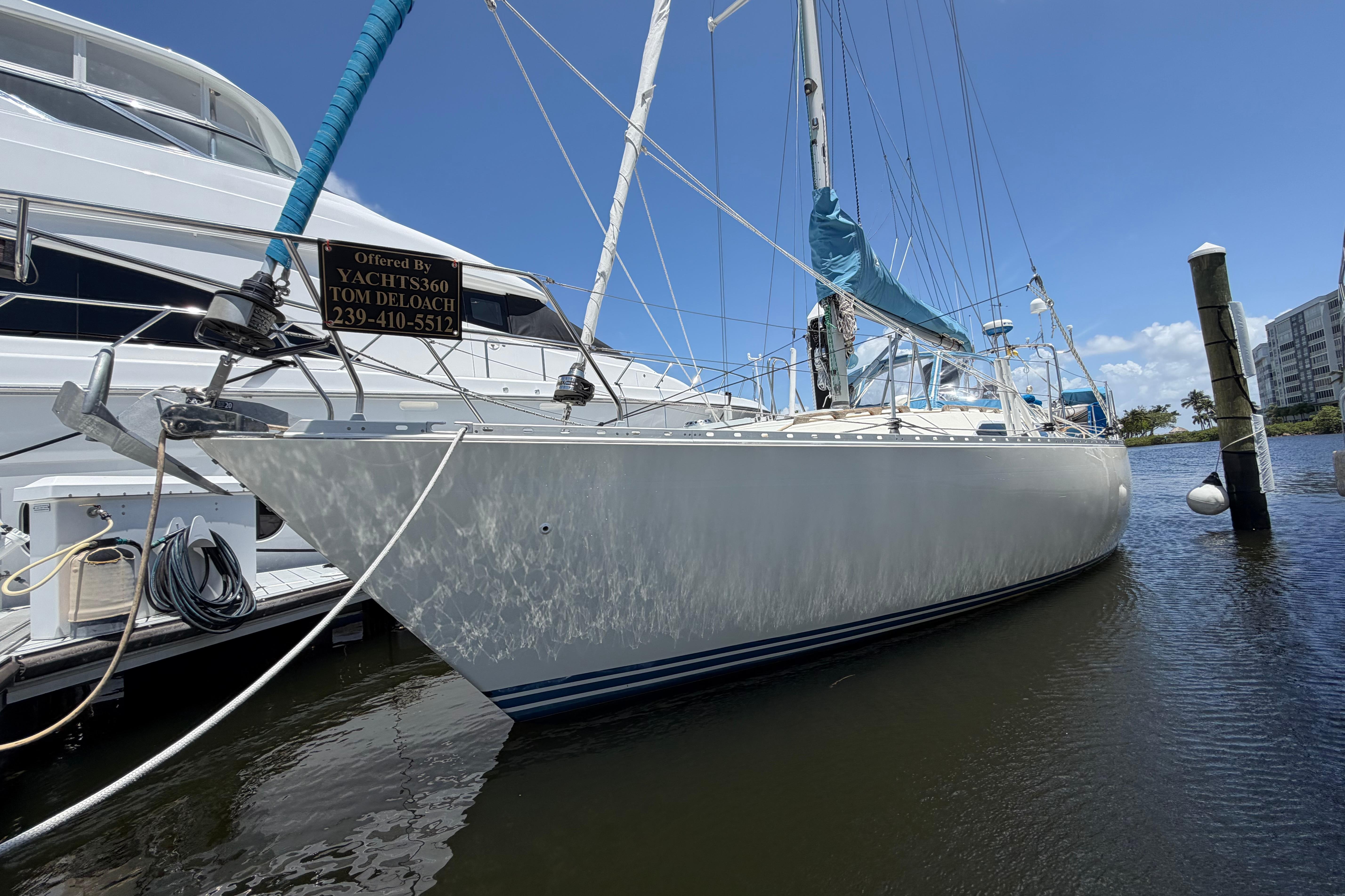 1987 Moody 376 sailboat docked, featuring sleek design and blue sail cover under clear skies.