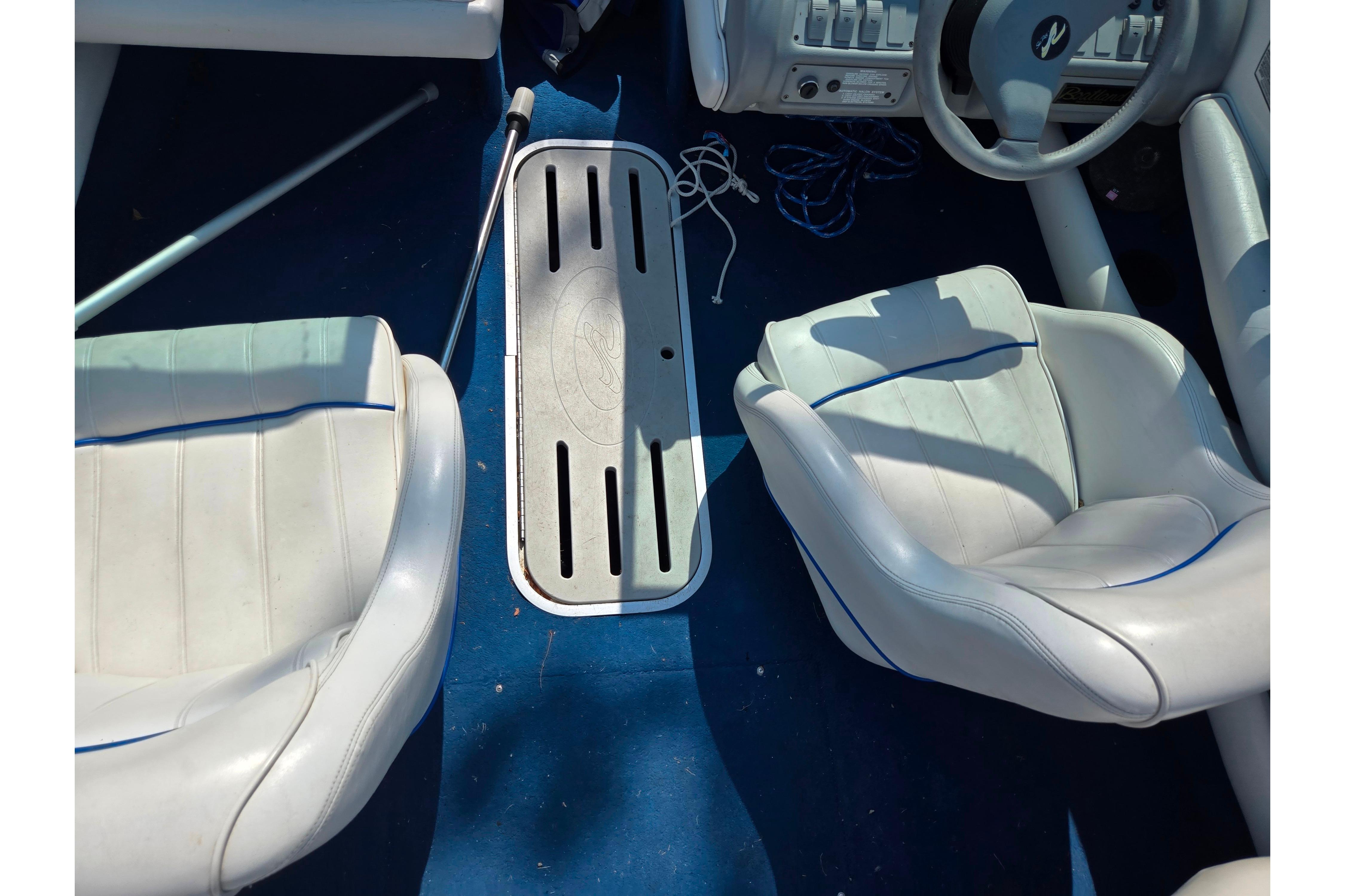 Interior of a 1994 Sea Ray 180 Bow Rider boat with white seats and blue carpet.
