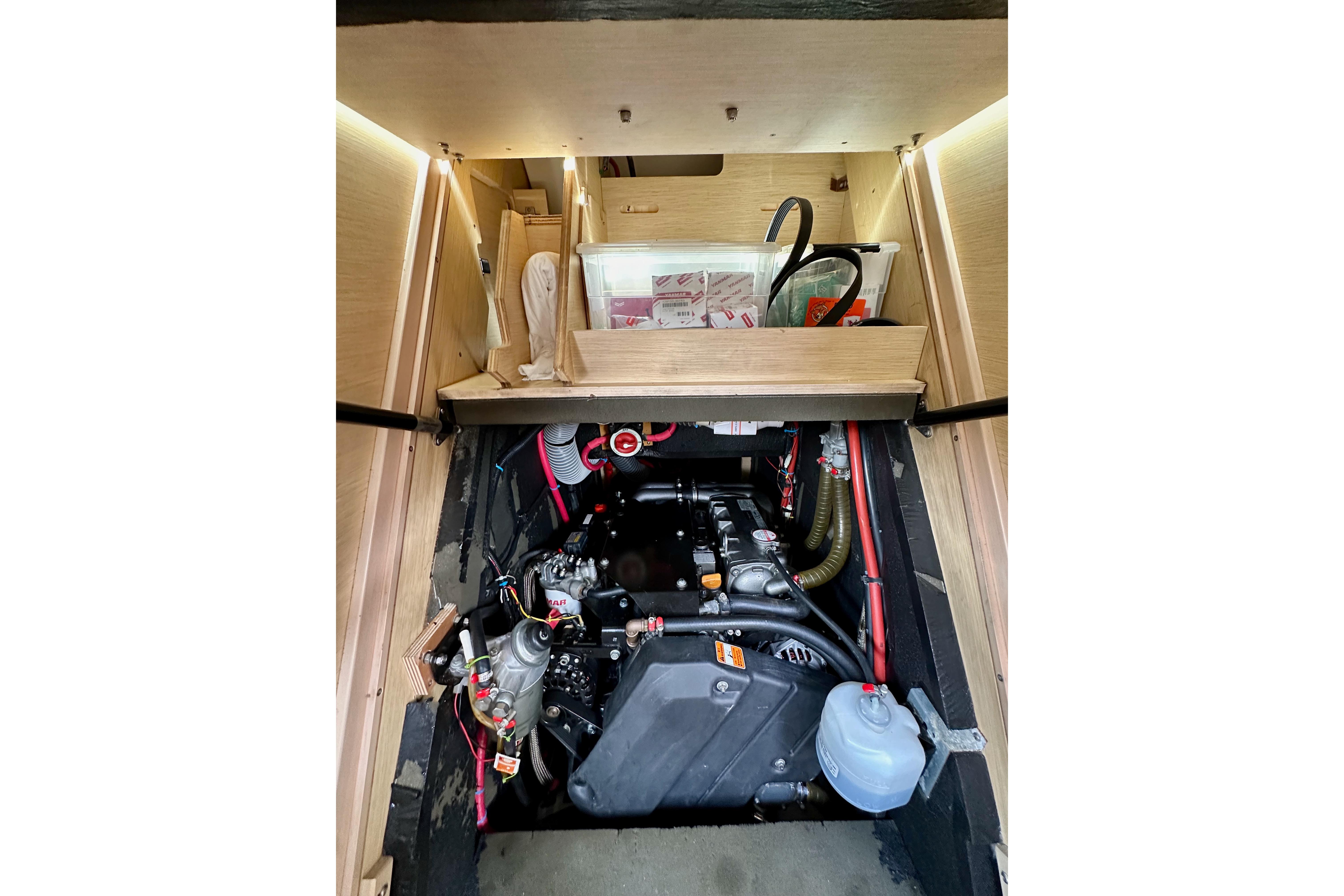 Engine compartment of a 2018 Jeanneau 54 sailboat, showcasing mechanical components and storage.