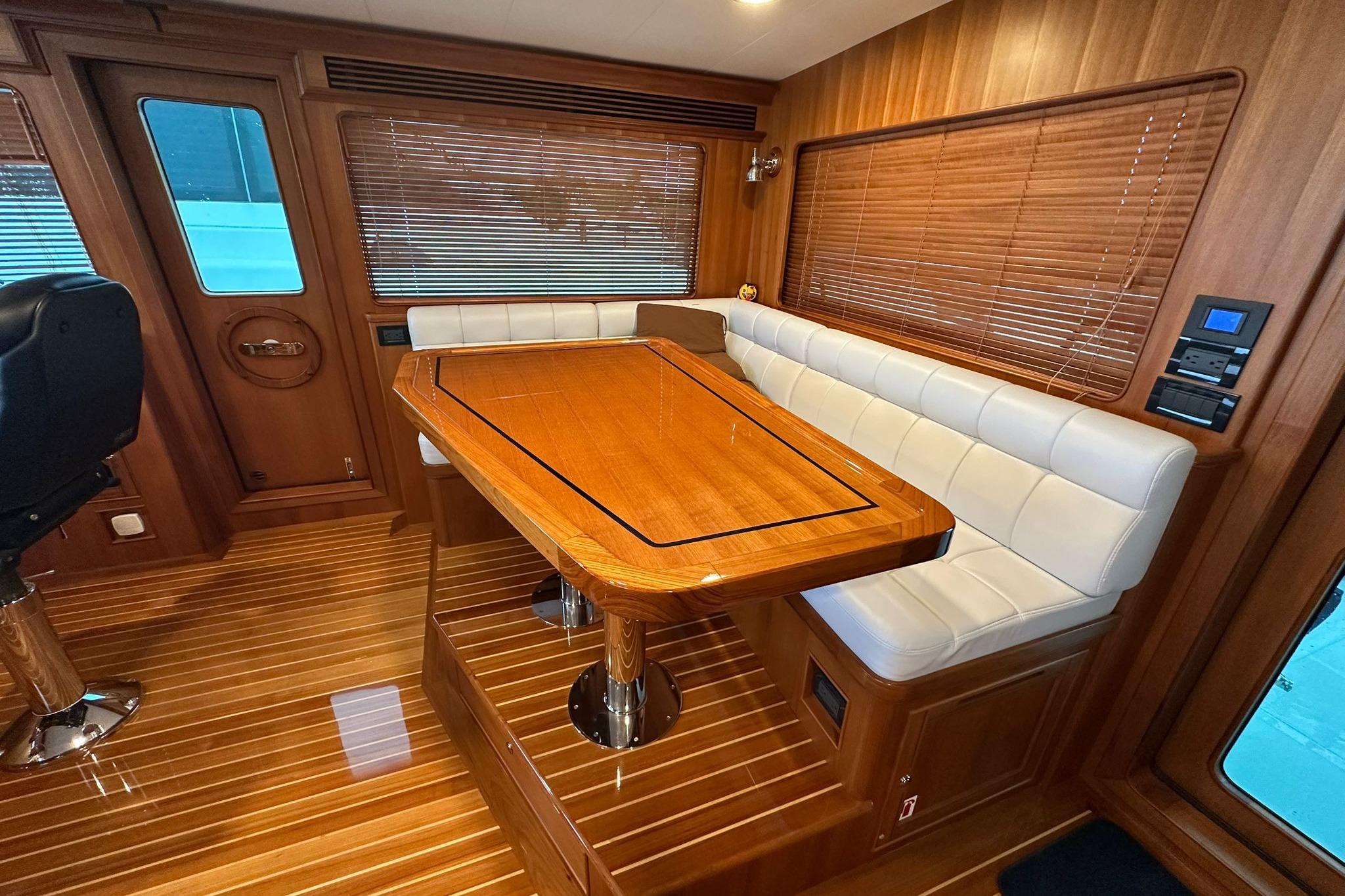 Luxurious interior of 2023 Marlow Explorer 66E-CB yacht with wooden table and white seating.