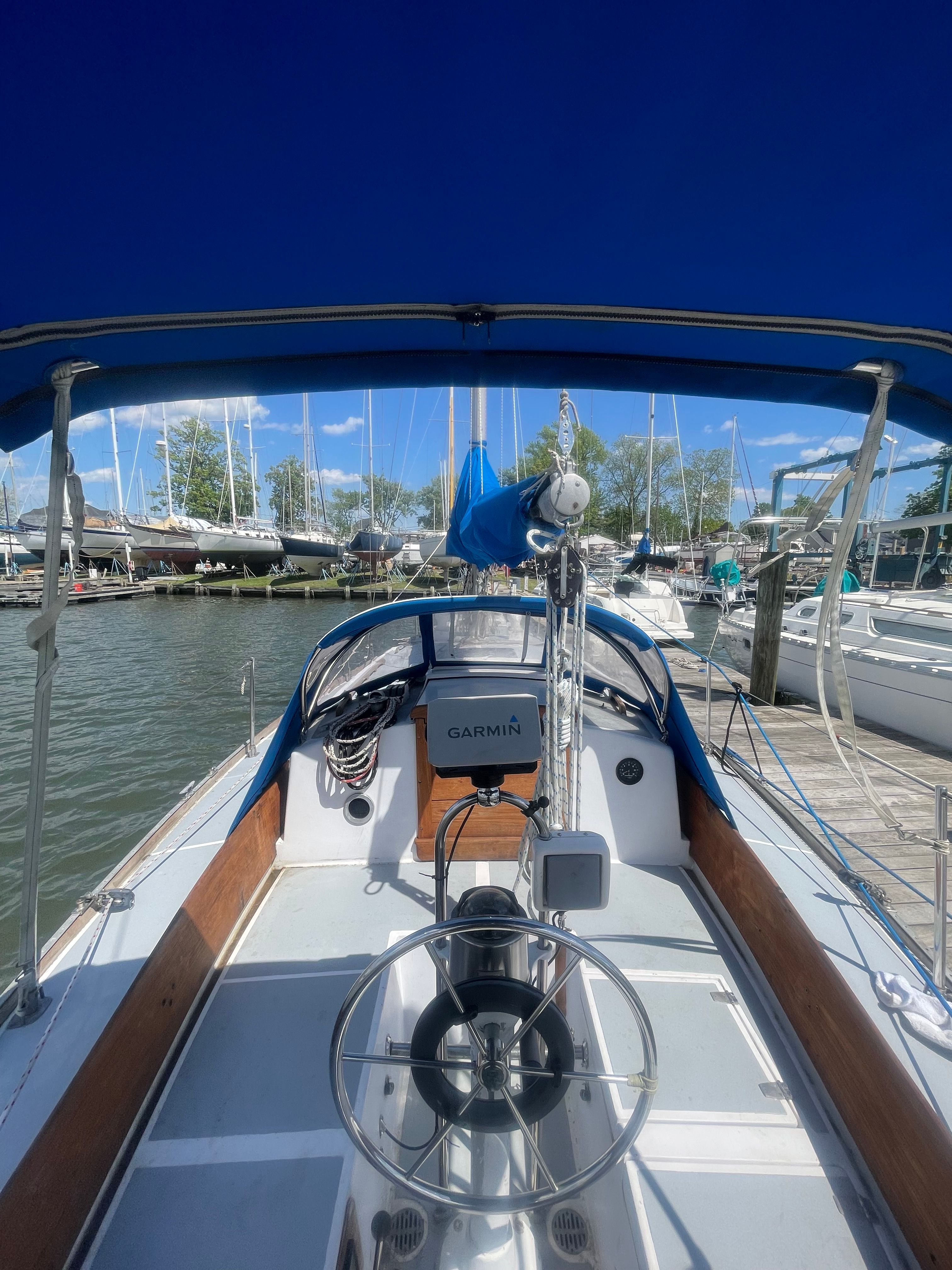 The cockpit of a Tartan 34 Classic yacht in a marina, surrounded by other boats.