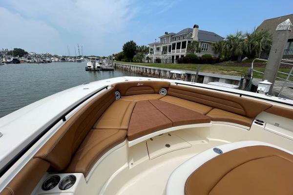2020 Scout 420 LXF boat with luxurious seating, docked near waterfront homes.
