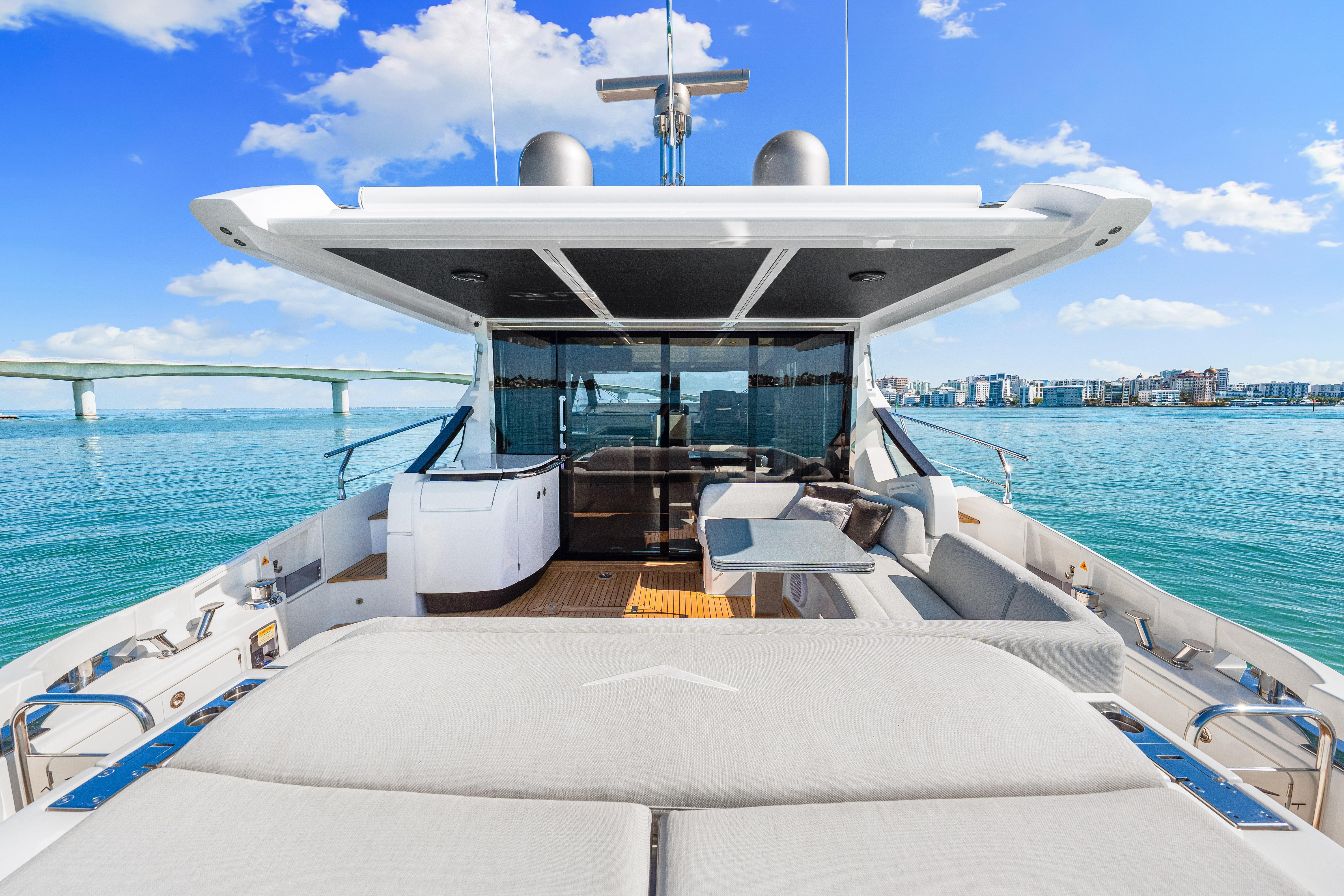 Luxurious 2020 Azimut S6 yacht deck with modern seating, overlooking serene blue waters and cityscape.