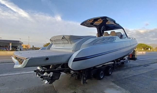 2025 SACS Rebel 47 boat on trailer, sleek design, parked outdoors under clear sky.