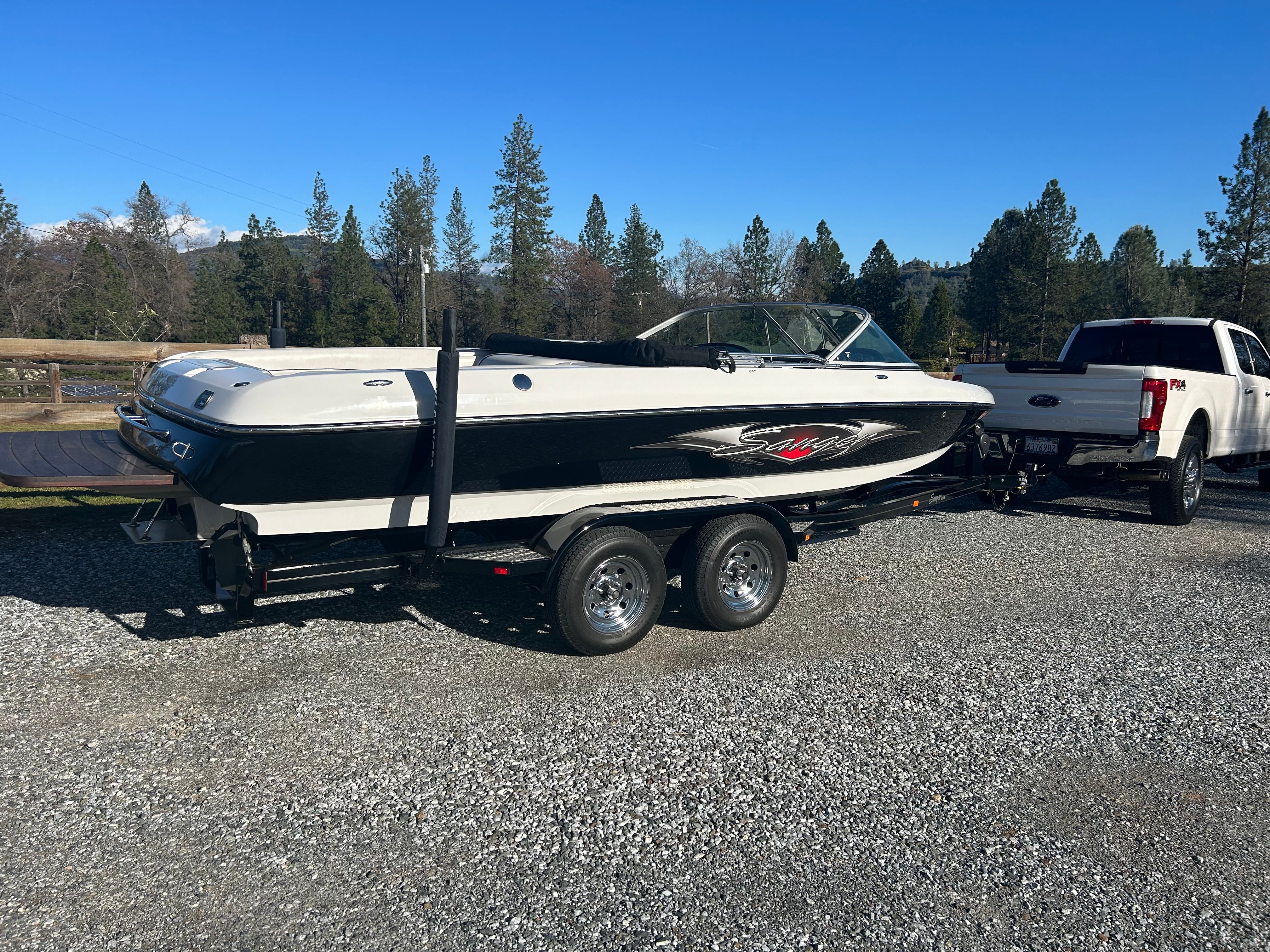 A 2007 Sanger boat on a trailer, parked next to a white pickup truck.