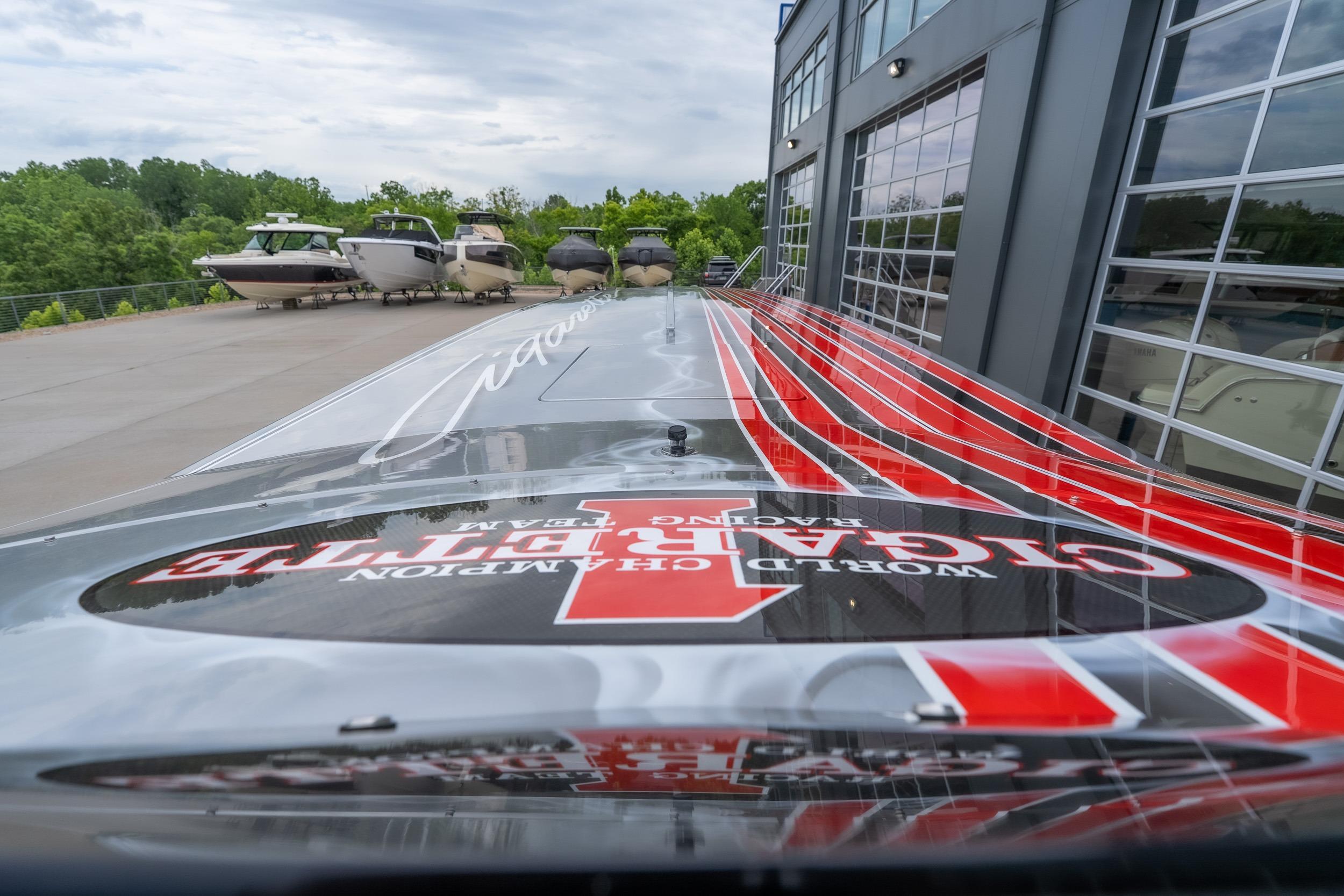 2006 Cigarette 39' Top Gun Unlimited boat with striking red and black design near a marina.