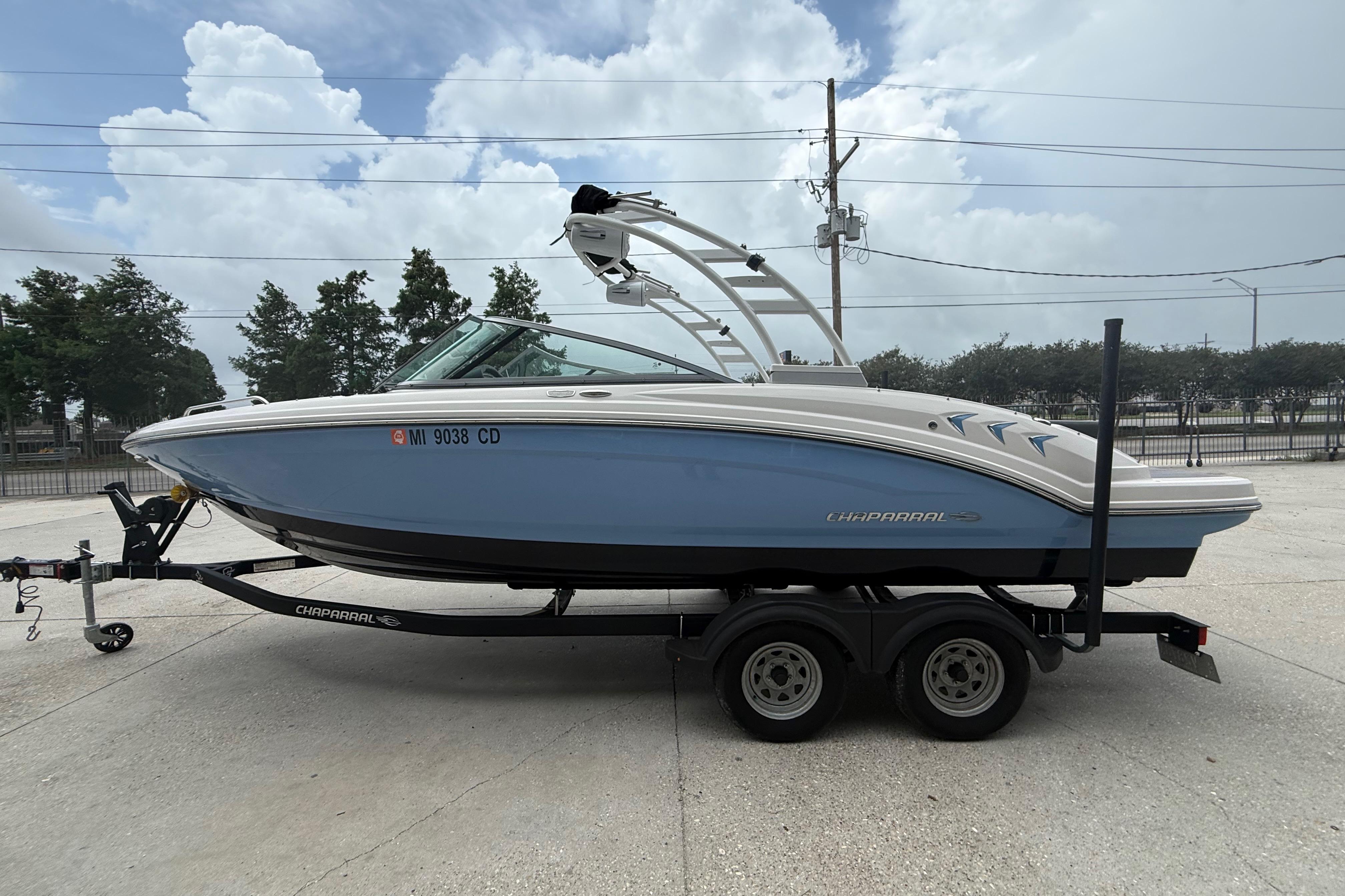 2023 Chaparral 230 SSi boat on trailer, parked outdoors under cloudy sky.