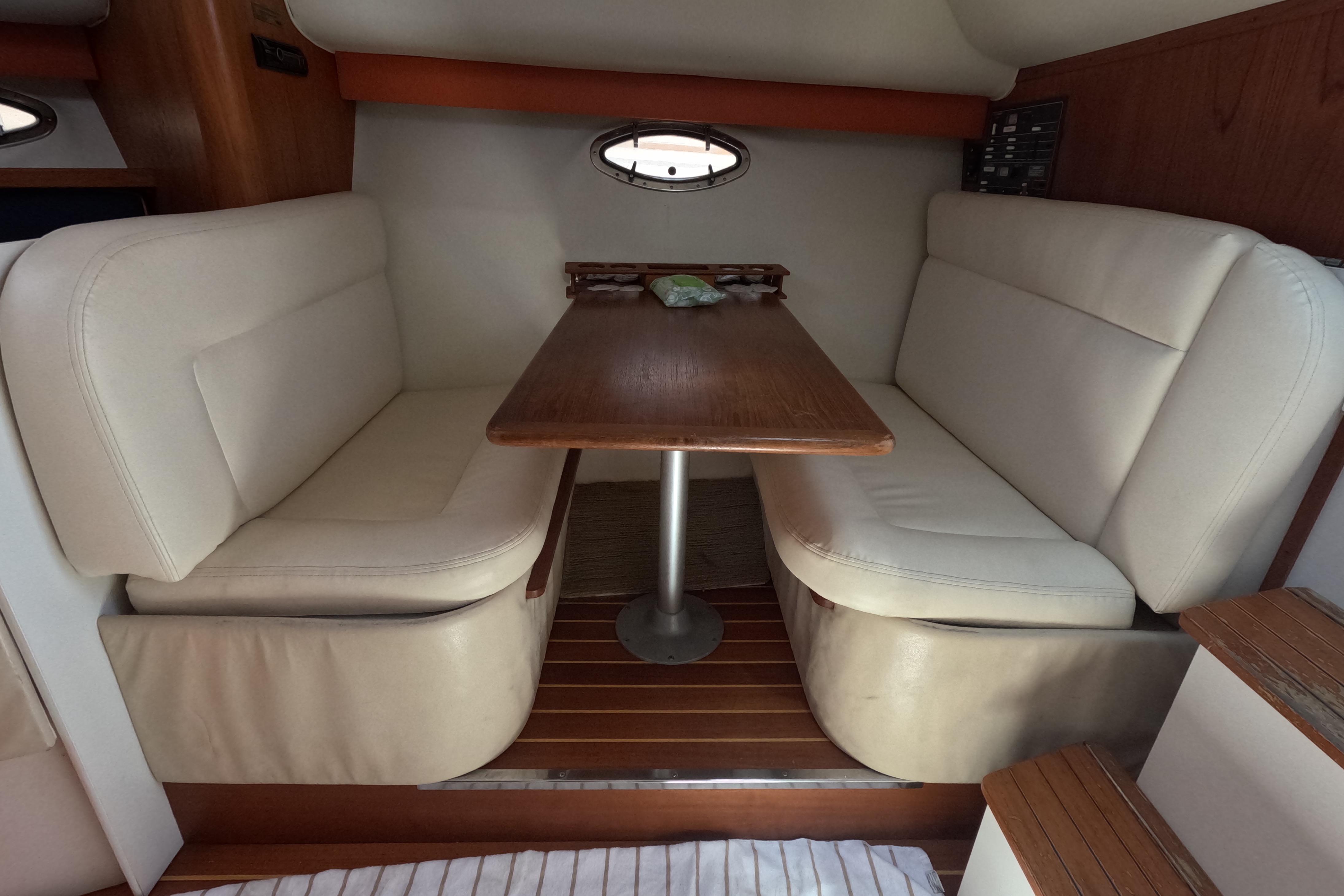 Interior of 1995 Tiara Yachts 2900 Open with beige seating and wooden table.