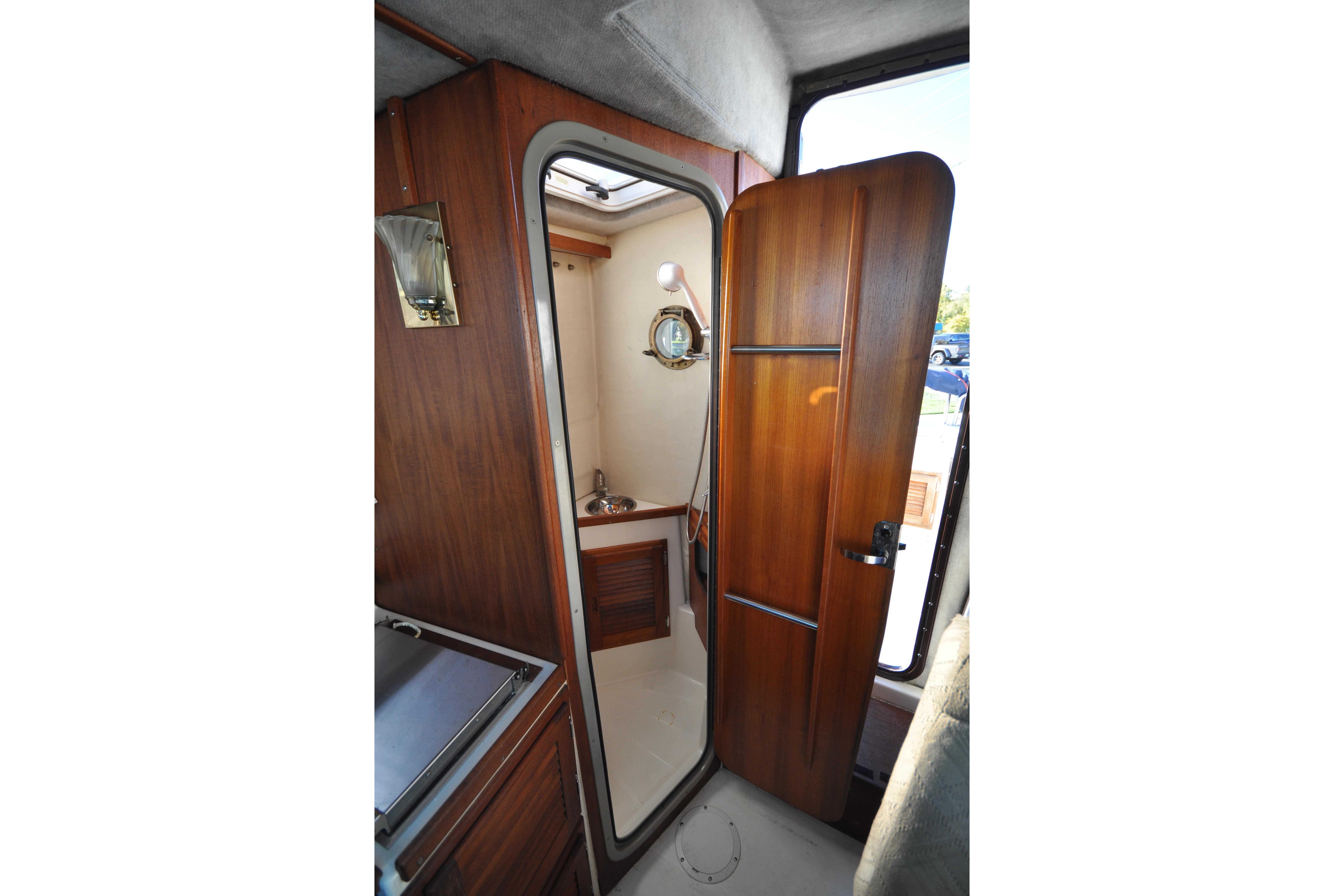 Interior view of 2007 Ranger Tugs R-25 boat bathroom with wooden door and compact sink.
