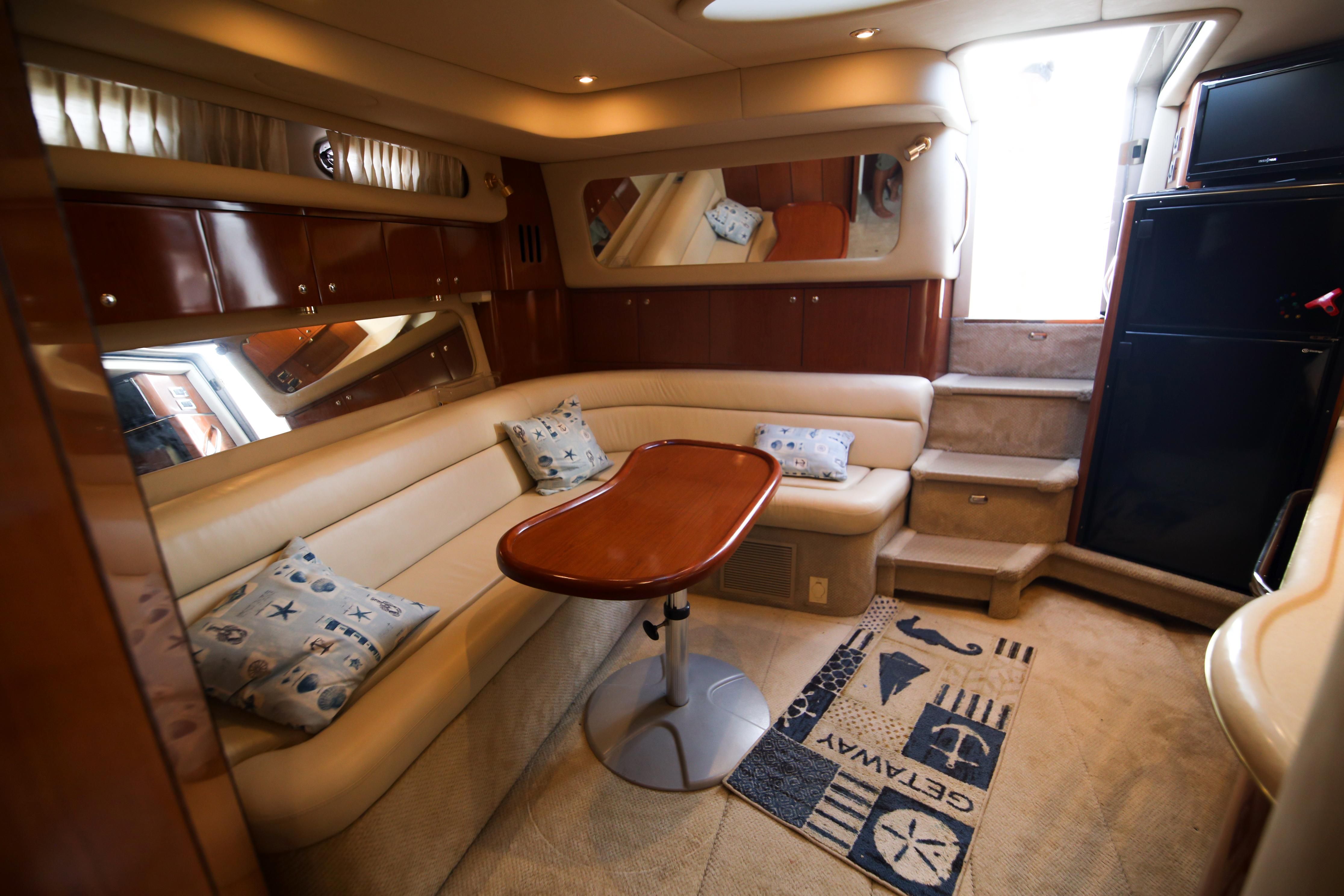Interior of the 2002 Sea Ray 410 Express Cruiser with beige sofa and wooden table.