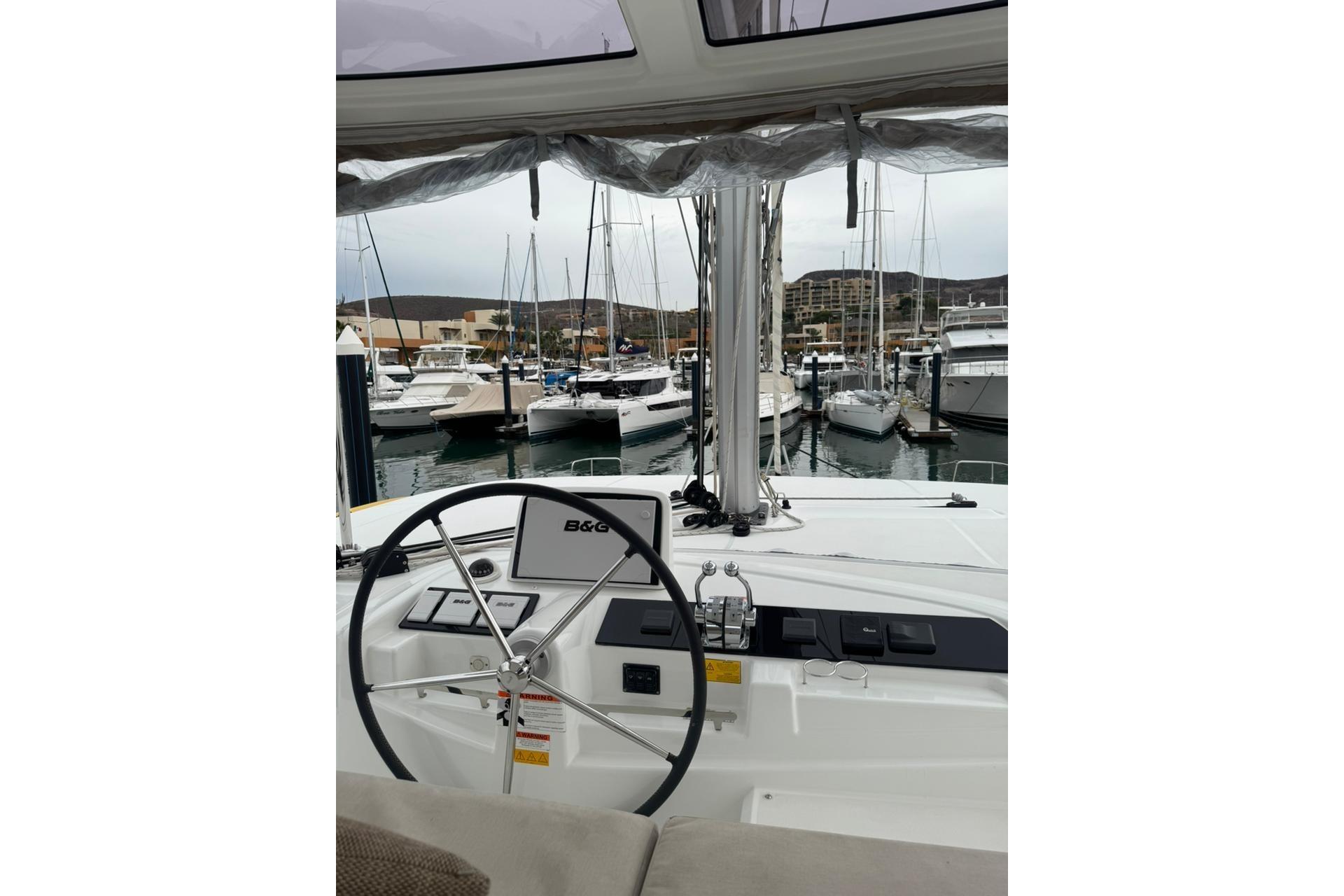 Helm of 2022 Lagoon 46 catamaran in marina, featuring B&G navigation system.