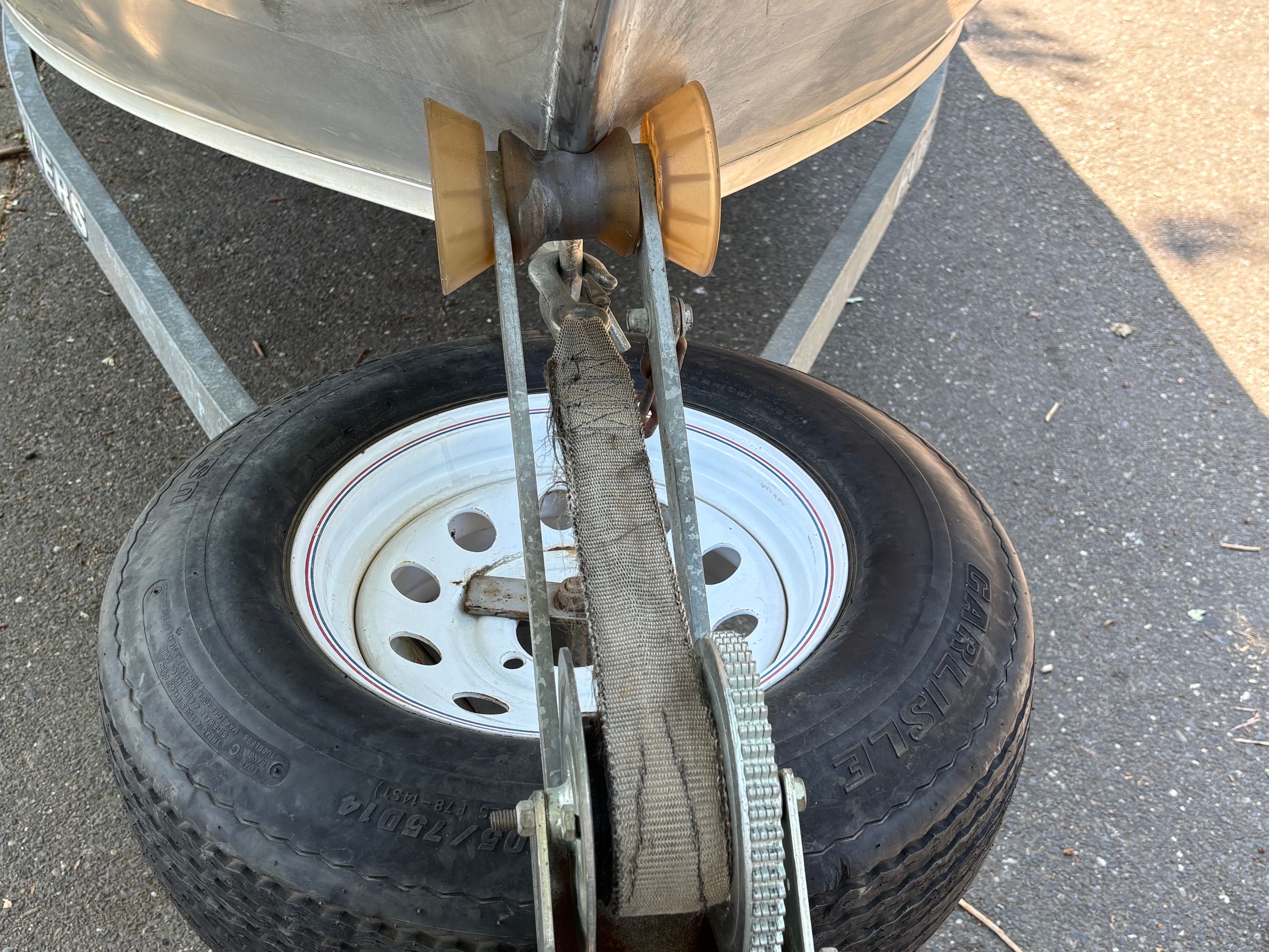 Close-up of a boat trailer with a spare tire and a winch.