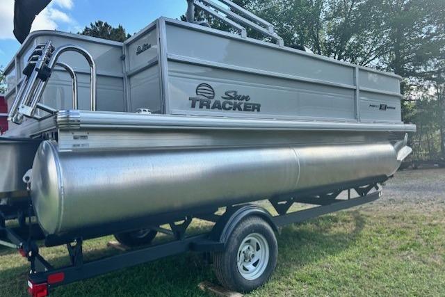 2026 Sun Tracker Party Barge 18 DLX pontoon boat on trailer, parked on grass.