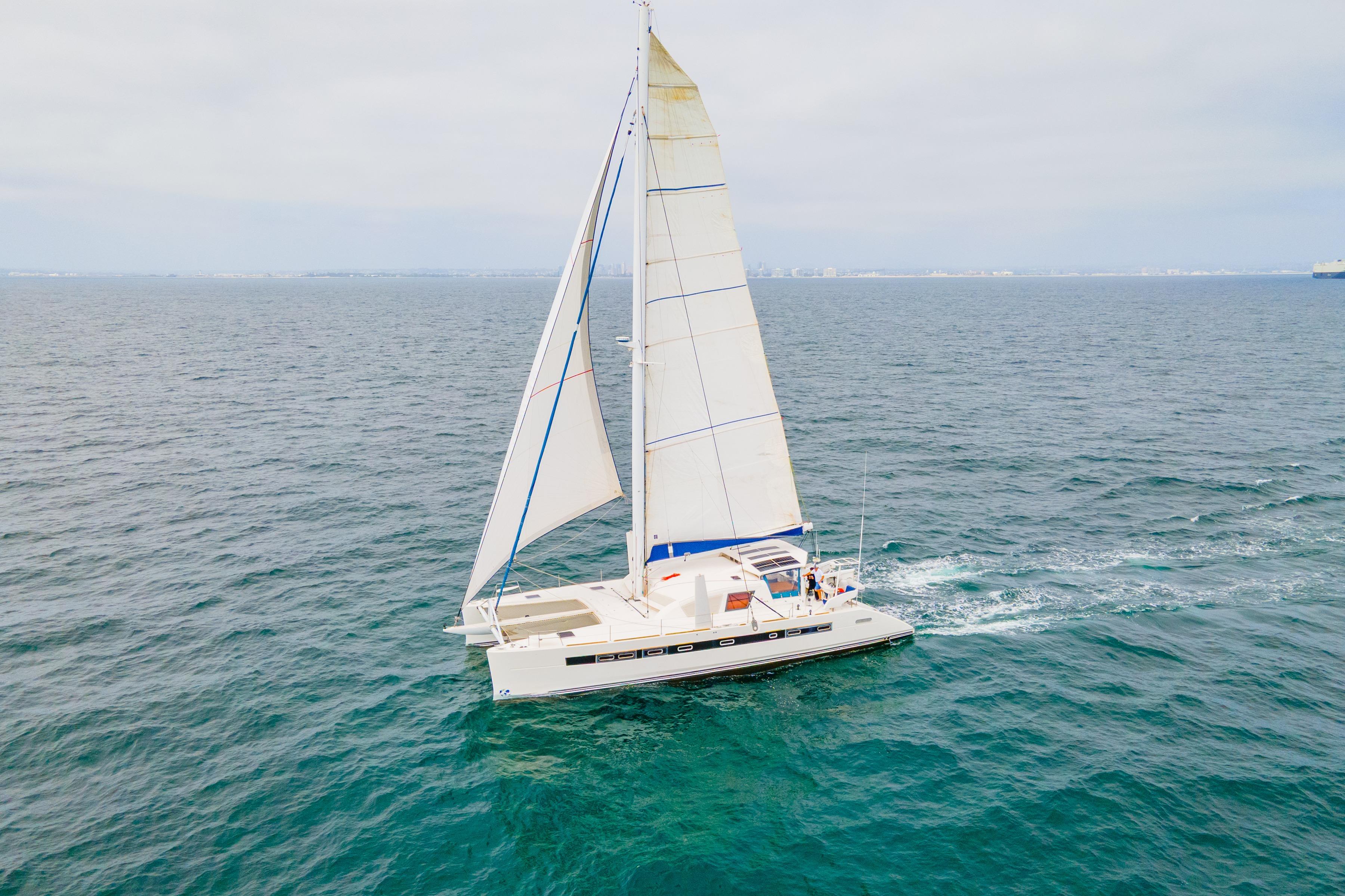 2009 Catana 65 sailing catamaran cruising on open sea under clear skies.