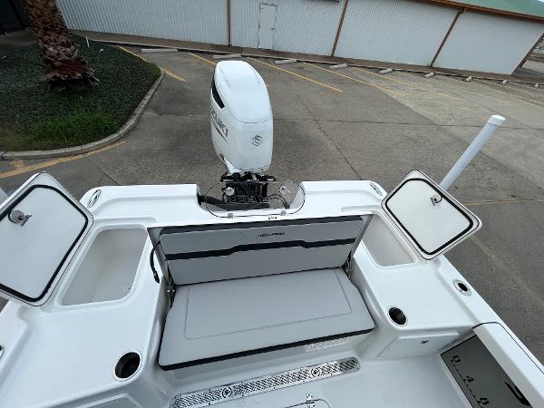 2024 Sea Pro 250 DLX boat with open storage compartments and outboard motor.