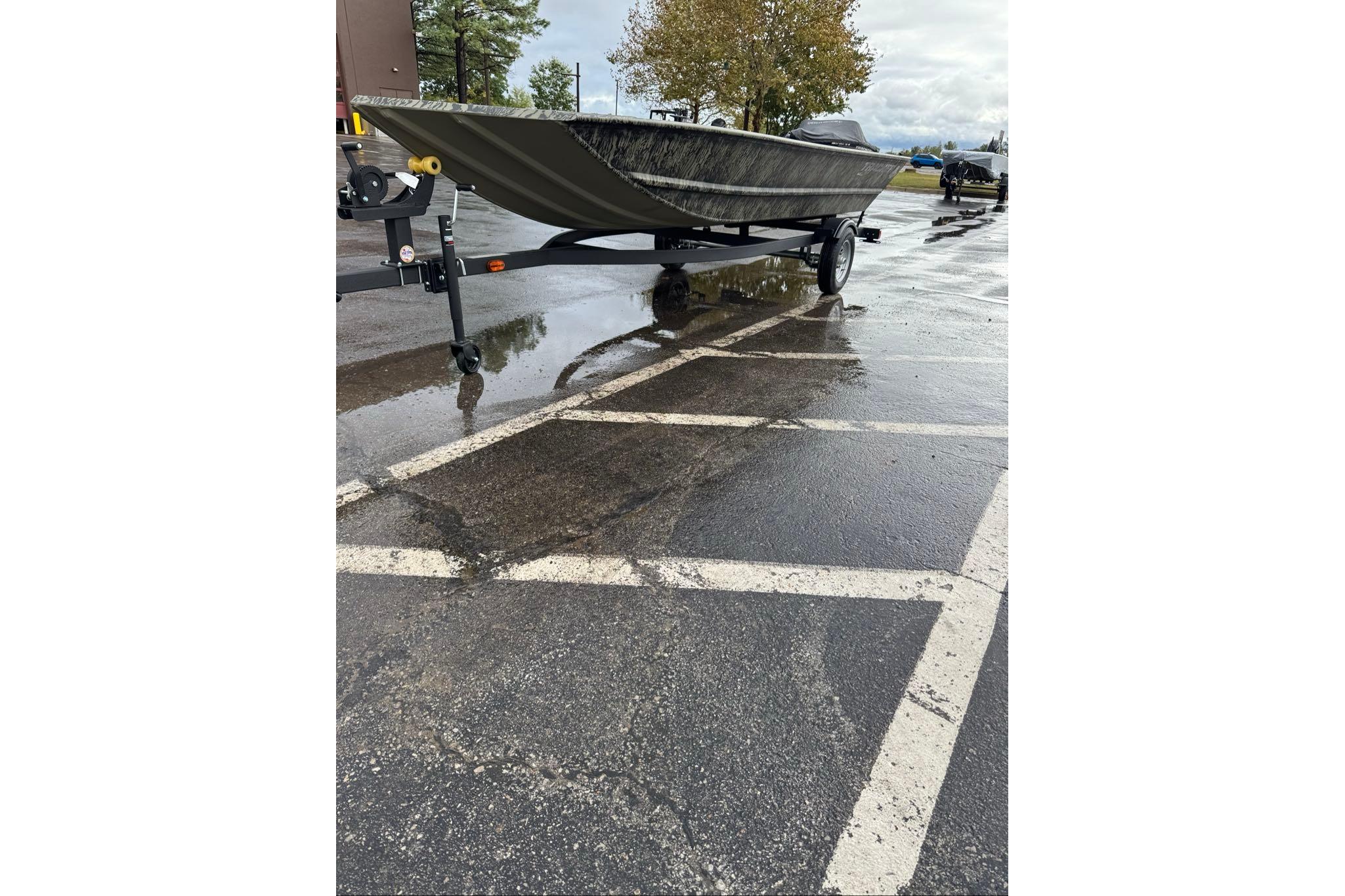 2026 Tracker Grizzly 1648 Utility boat on trailer in wet parking lot.