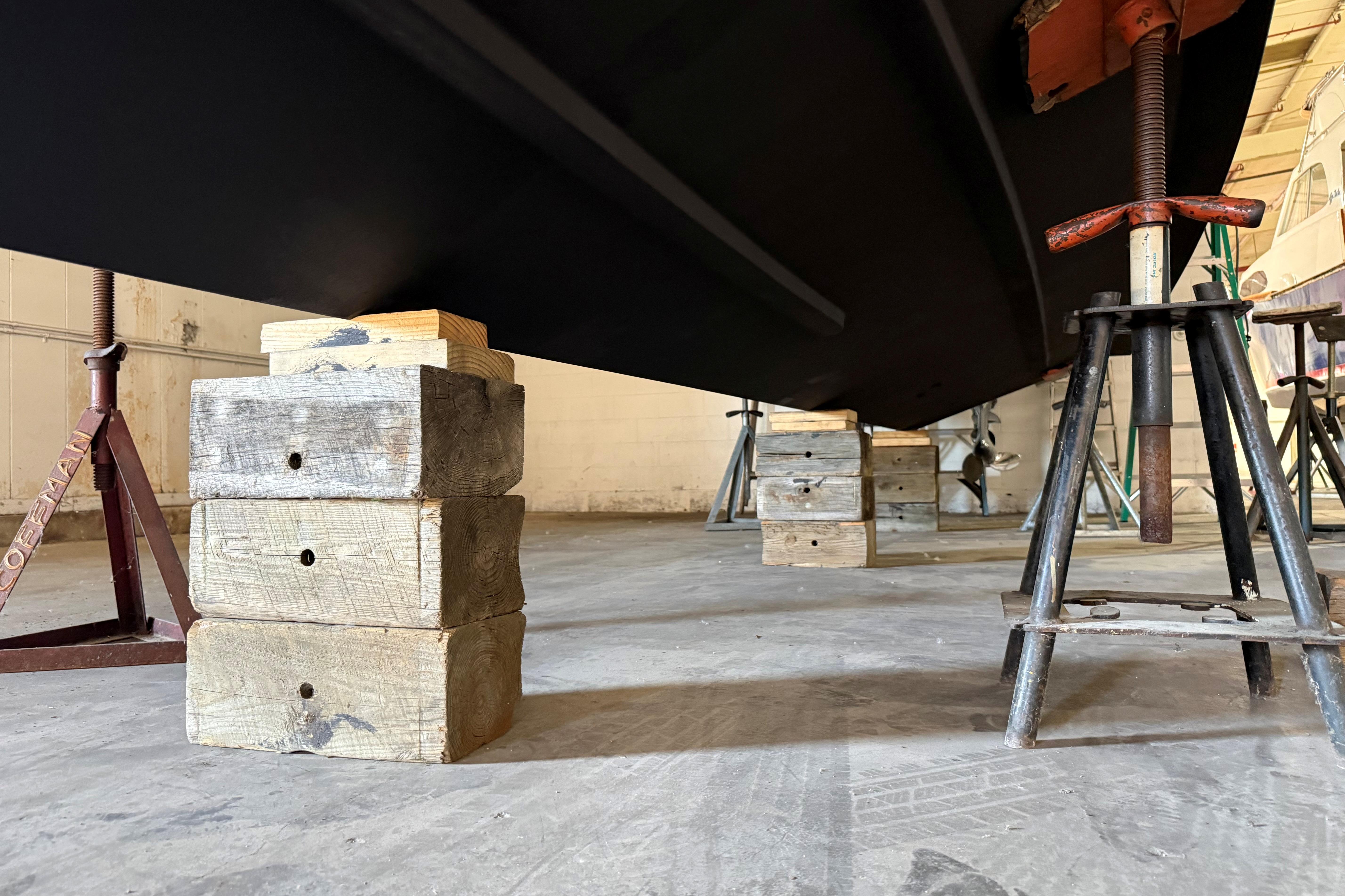 2021 Pursuit S 268 Sport boat hull supported by wooden blocks and metal stands.