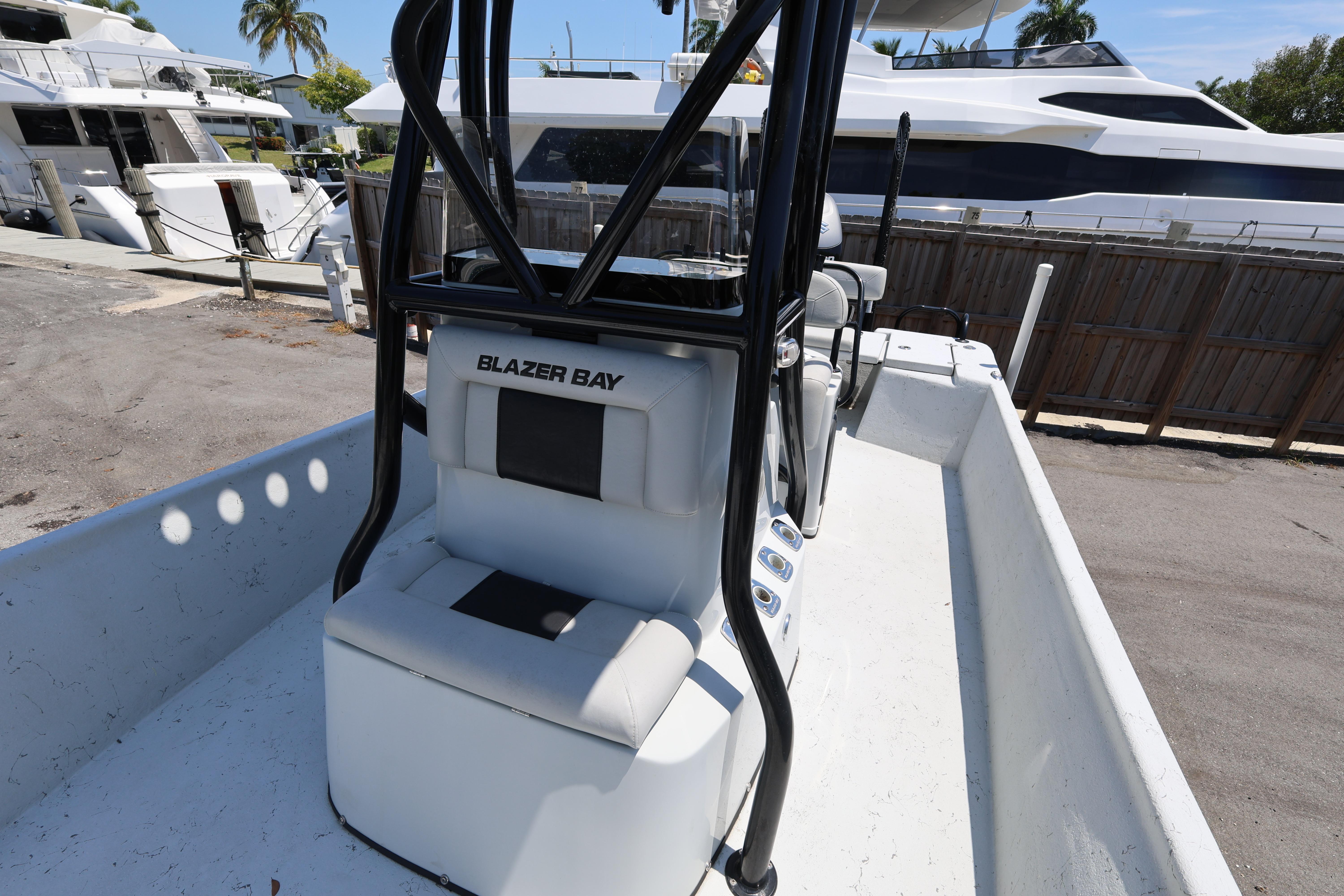 2021 Blazer Bay 2400 boat interior with seating and console, docked near luxury yachts.