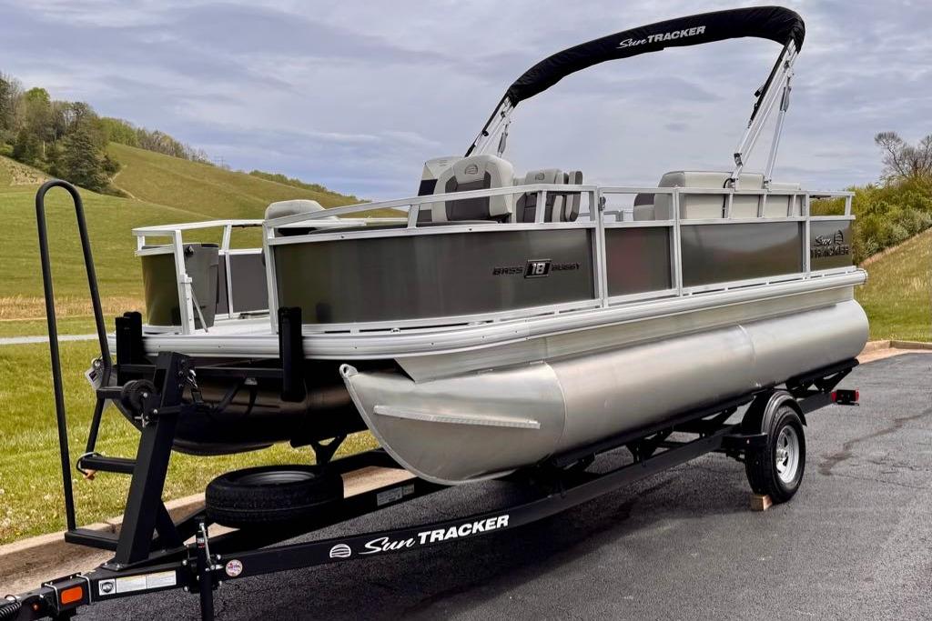 2026 Sun Tracker Bass Buggy 18 DLX pontoon boat on trailer, parked outdoors.