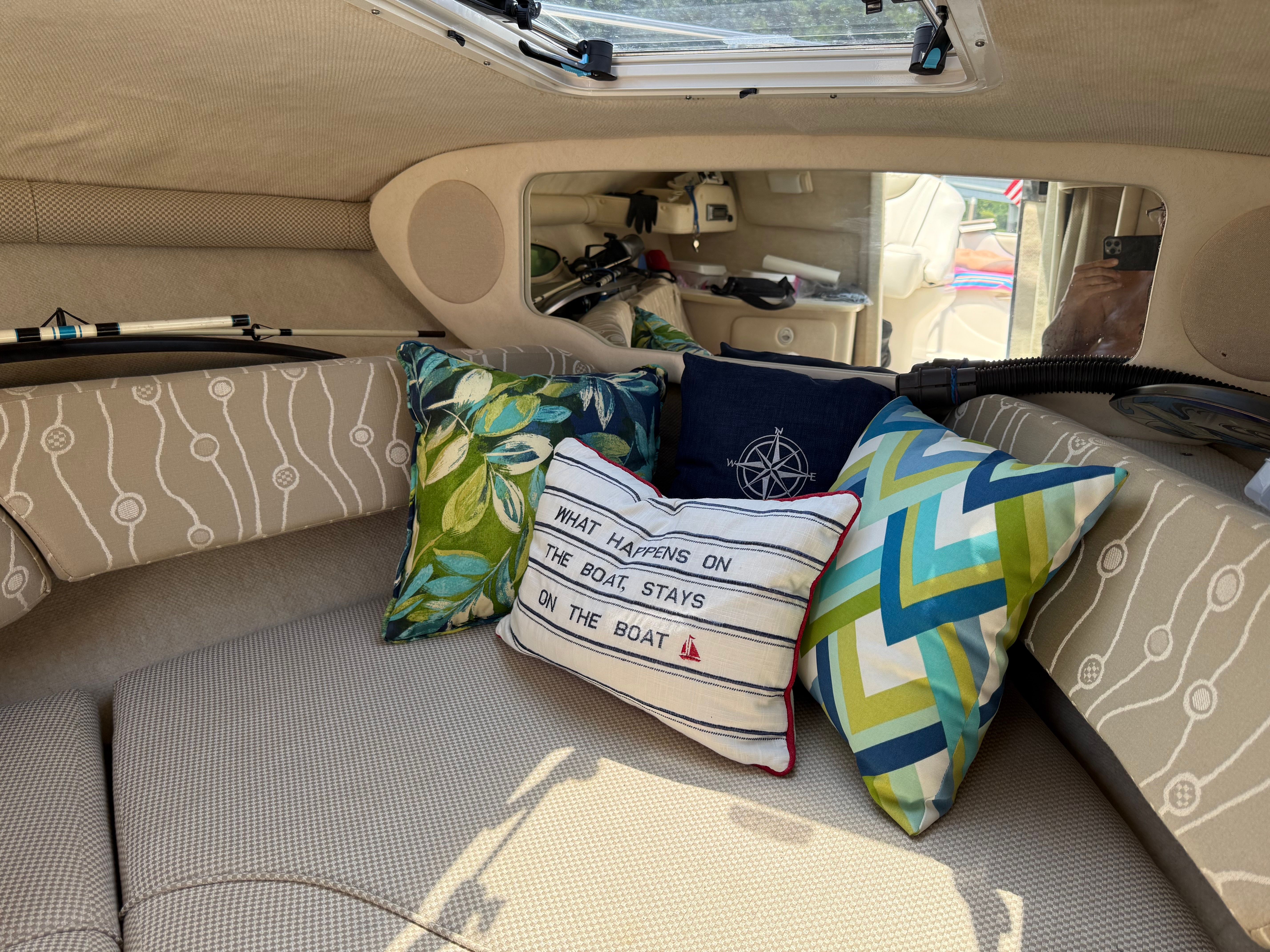 Interior of a Sea Ray 215 Weekender boat with decorative pillows.