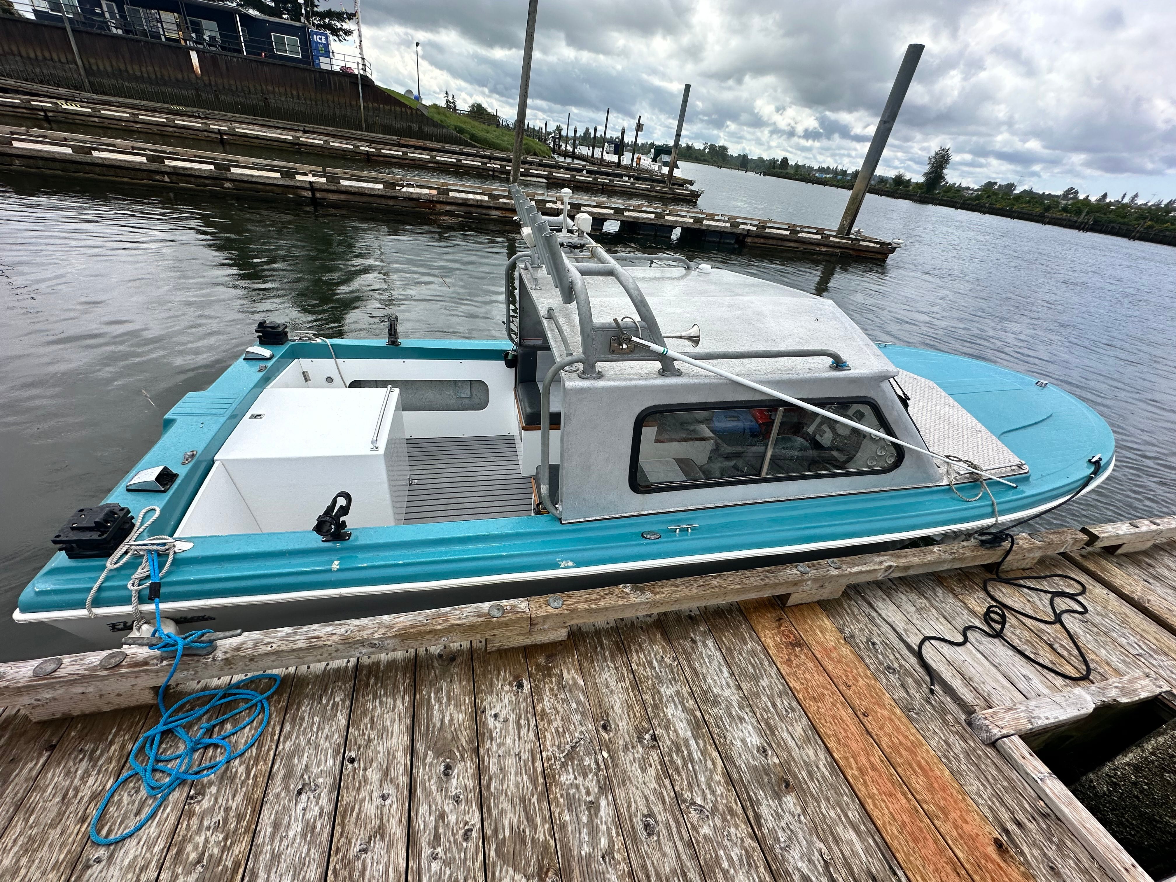 A restored 1967 Fiberform boat docked at a wooden pier. It features a turquoise exterior.