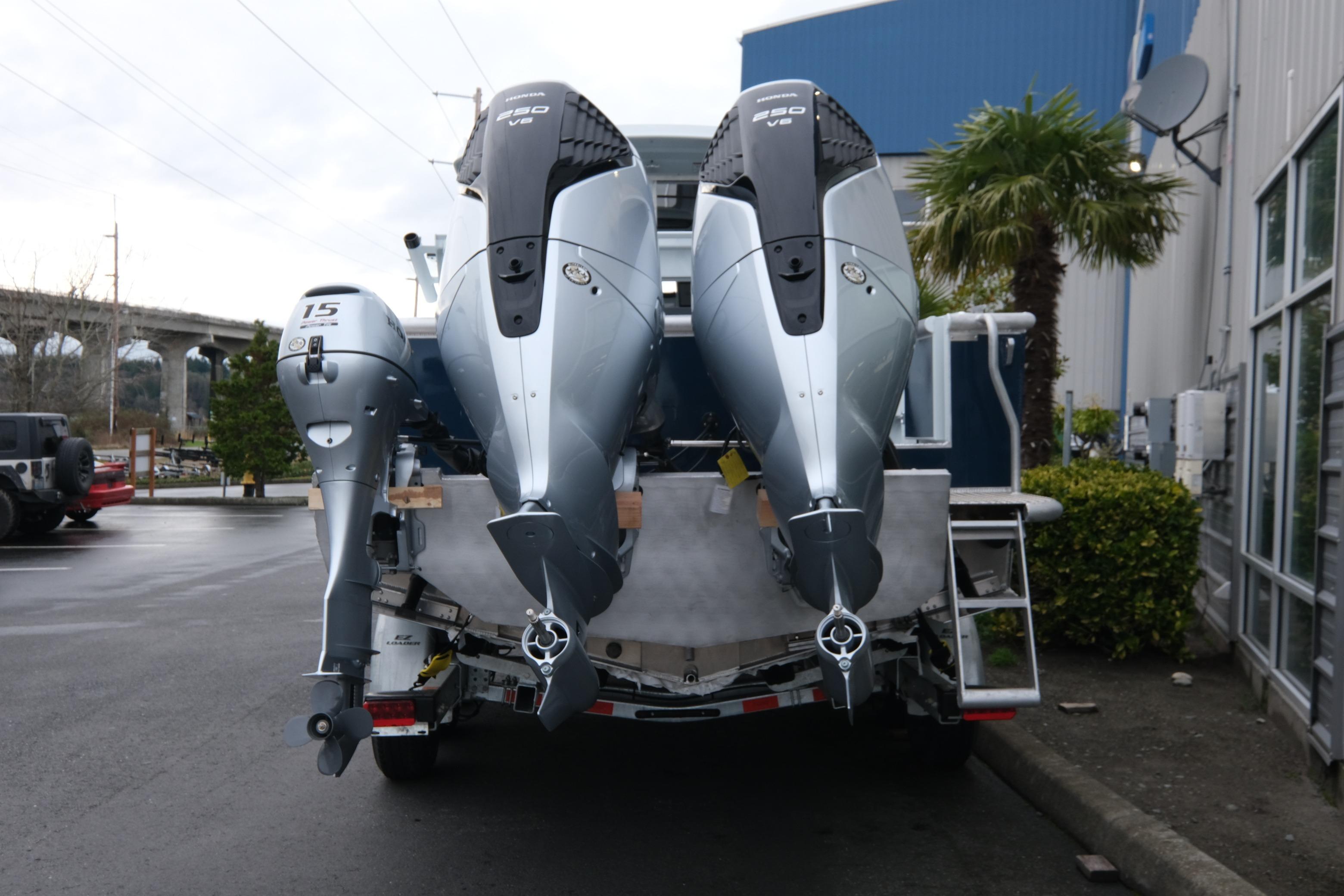 2026 Hewescraft 270 Pacific Explorer with dual outboard motors in a parking lot.