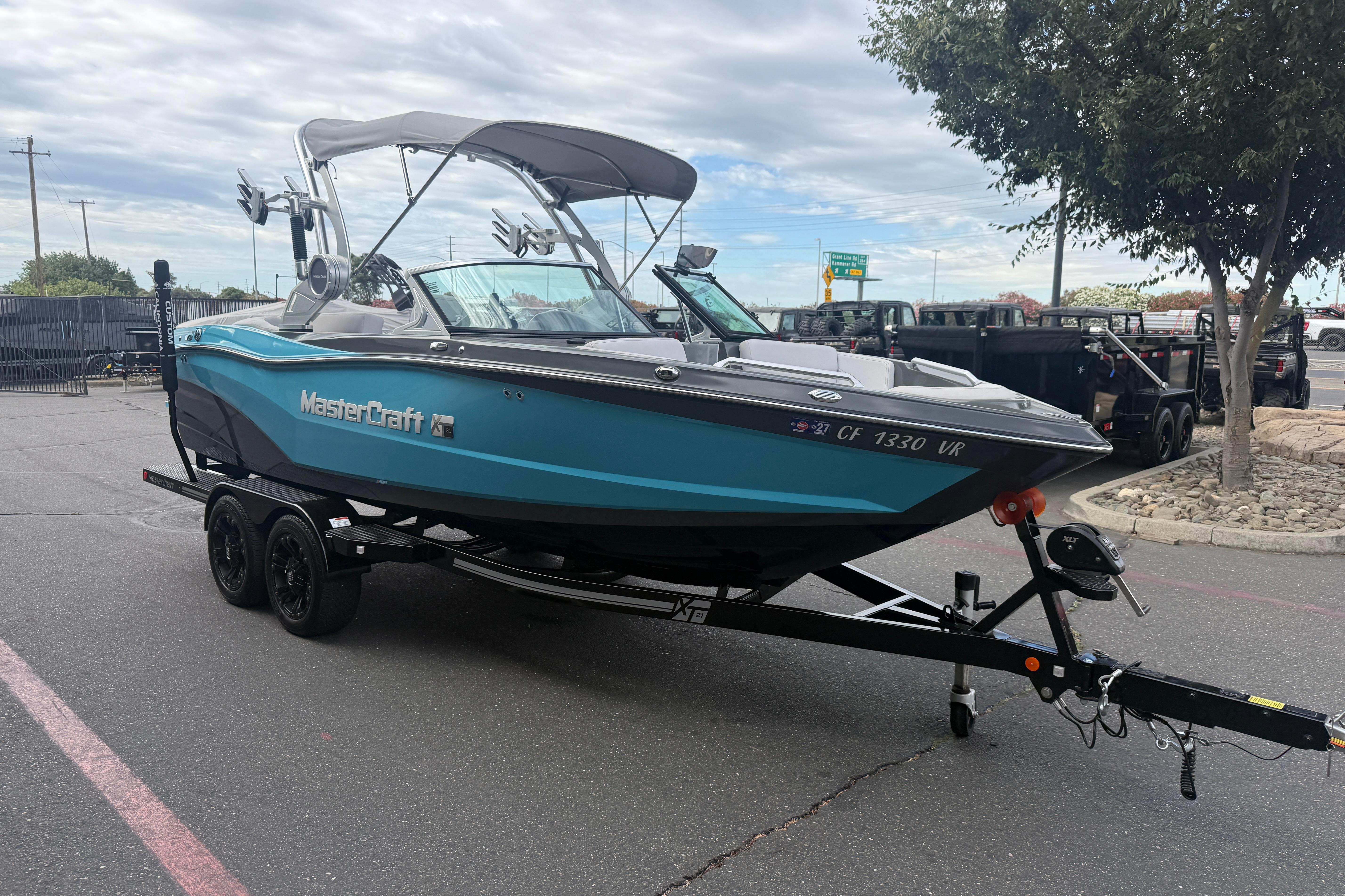 2018 MasterCraft XT21 boat on trailer, parked outdoors under cloudy sky.