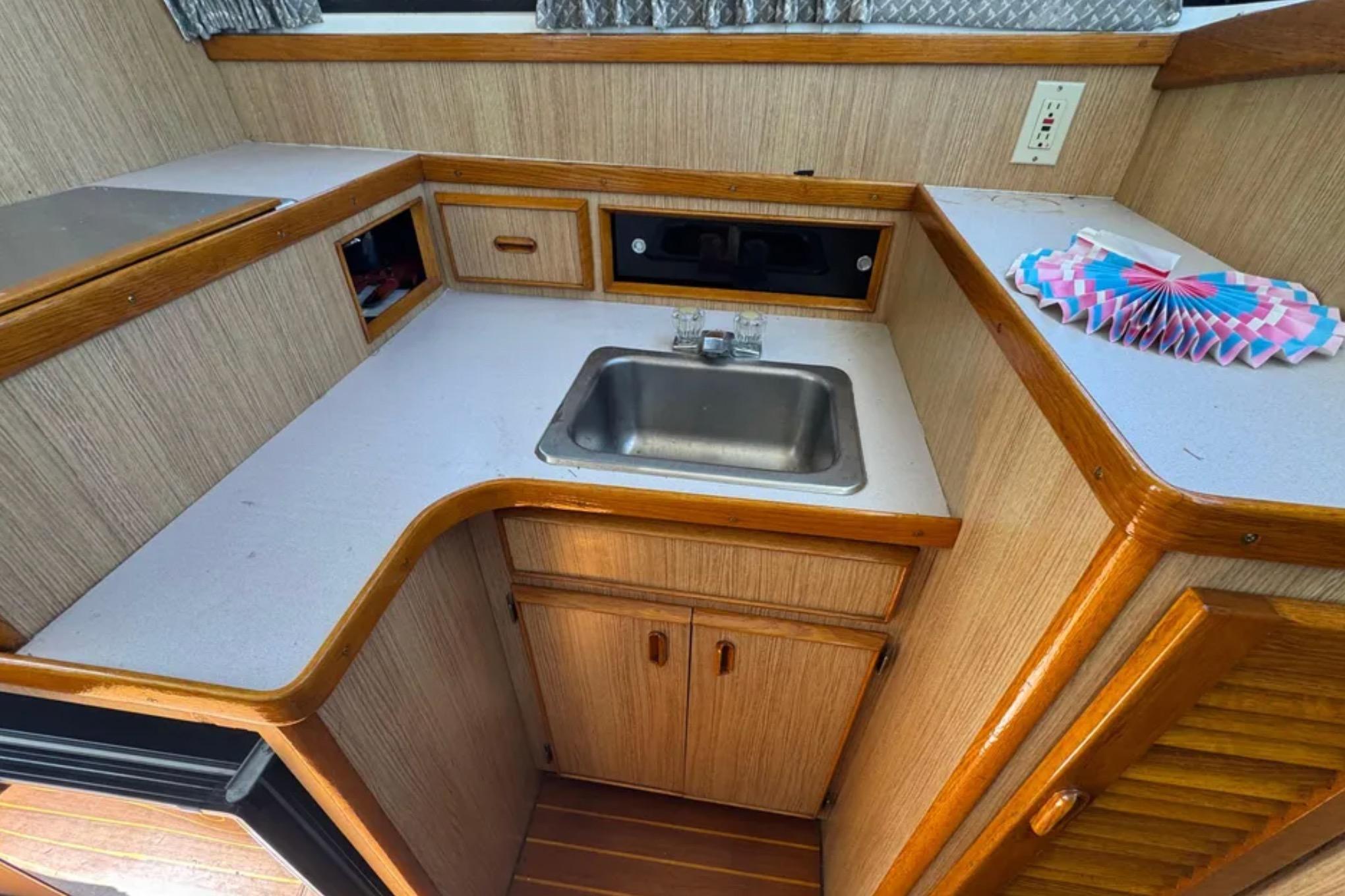 1988 Bertram 28 Sport Fisherman interior kitchen with sink and wooden cabinetry.