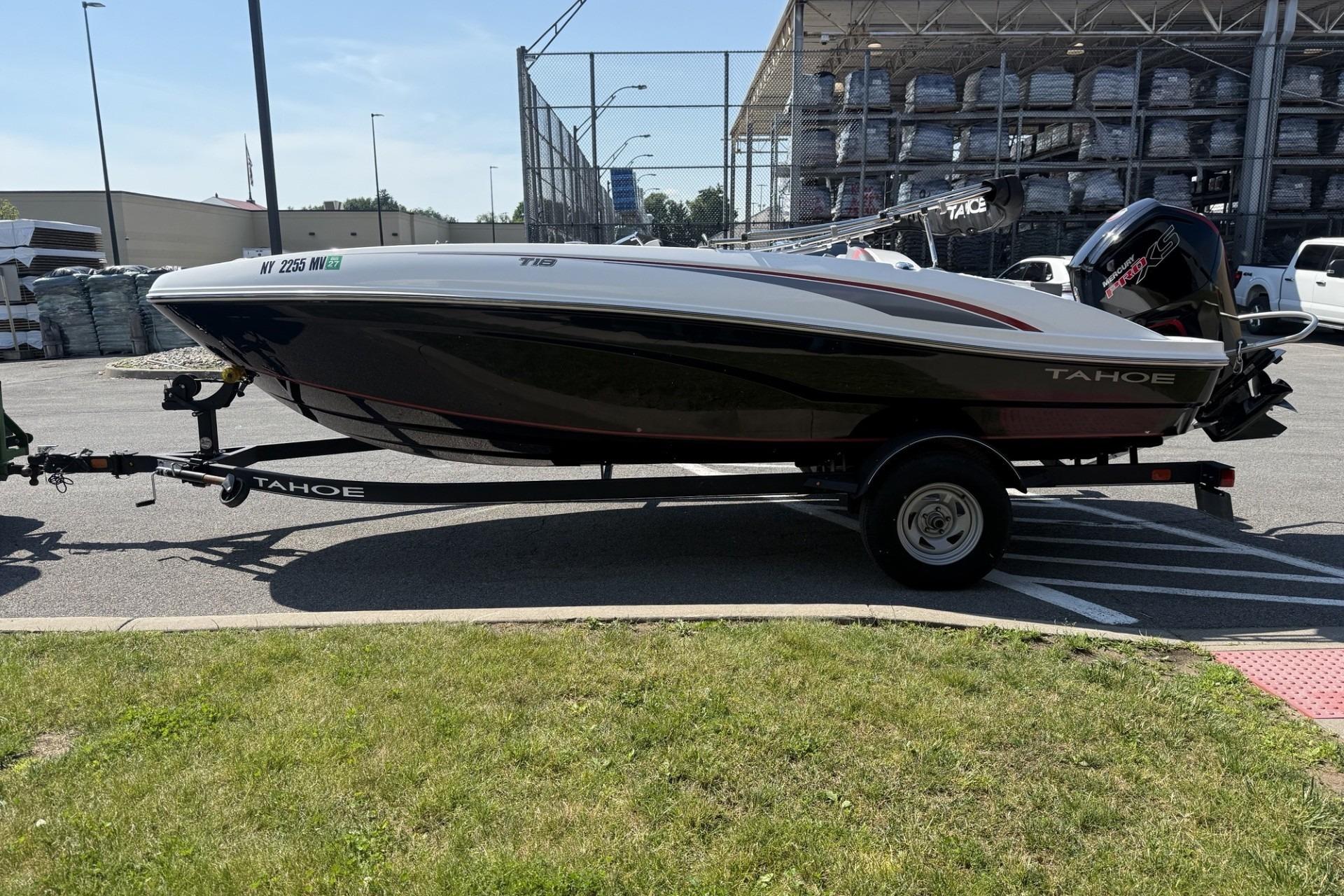 2024 Tahoe T18 boat on trailer in parking lot, side view.