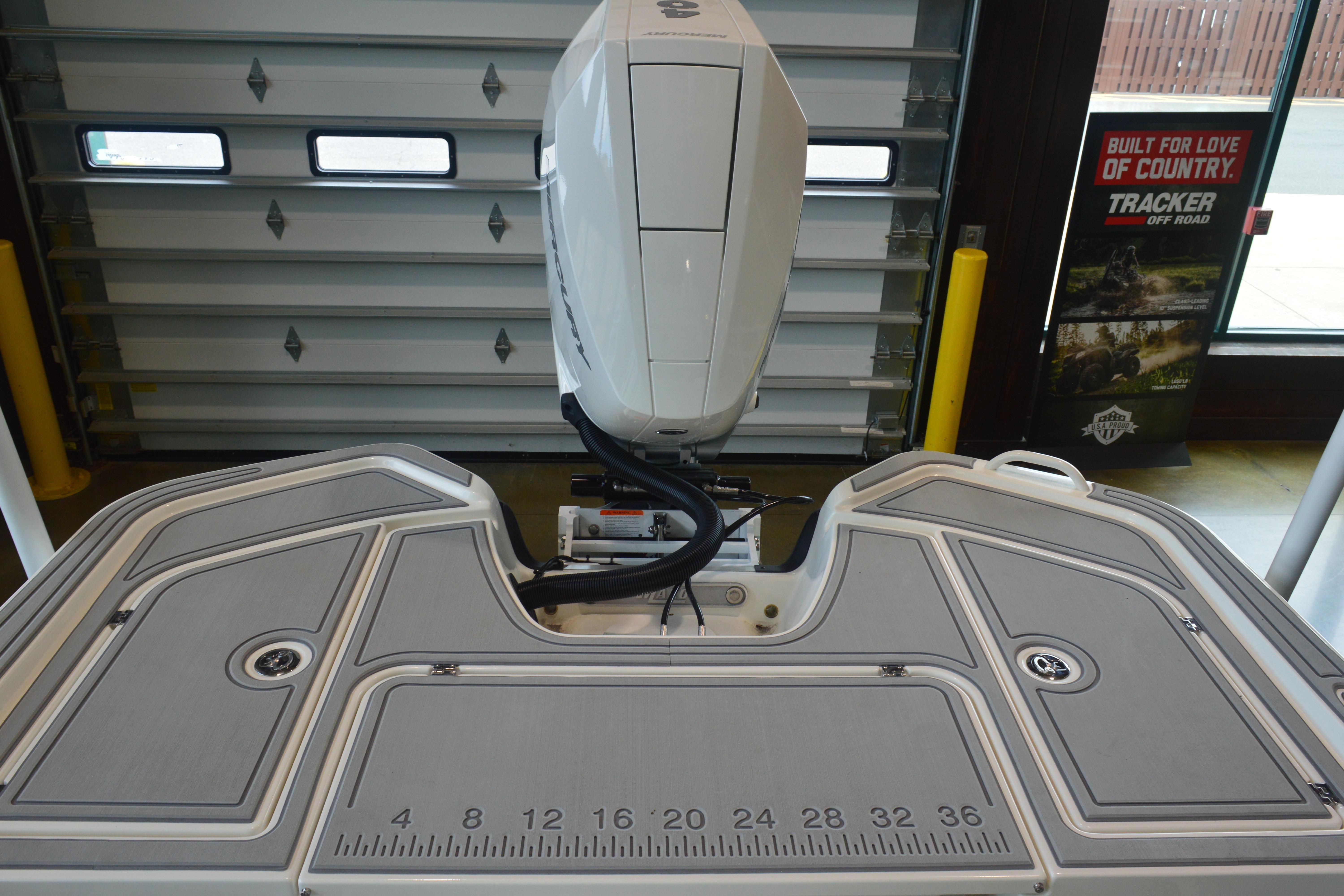 2026 Mako 24 APEX boat with outboard motor in showroom setting.