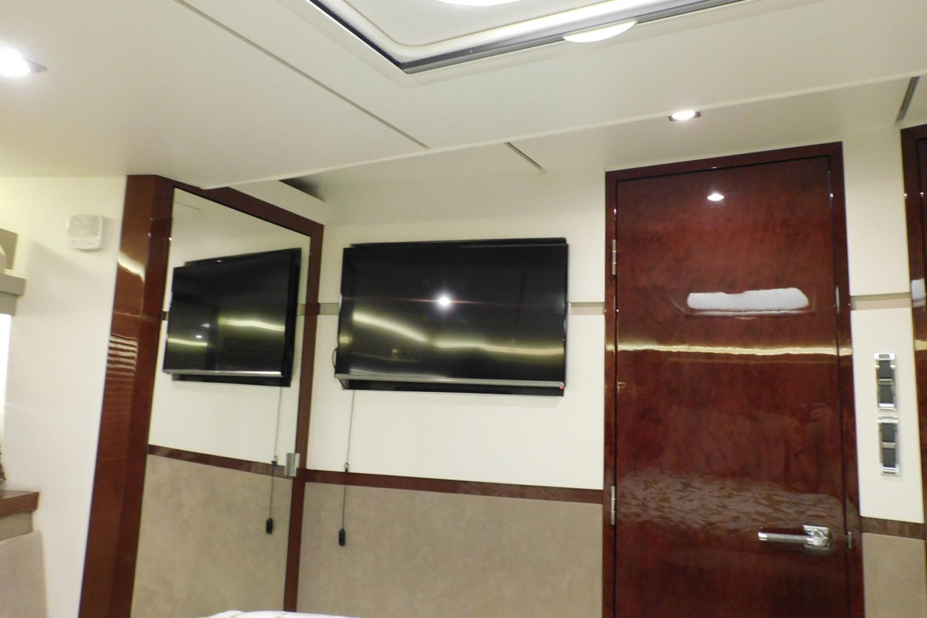 Luxurious interior of 2019 Sea Ray L550 yacht with mounted TV and polished wood finishes.