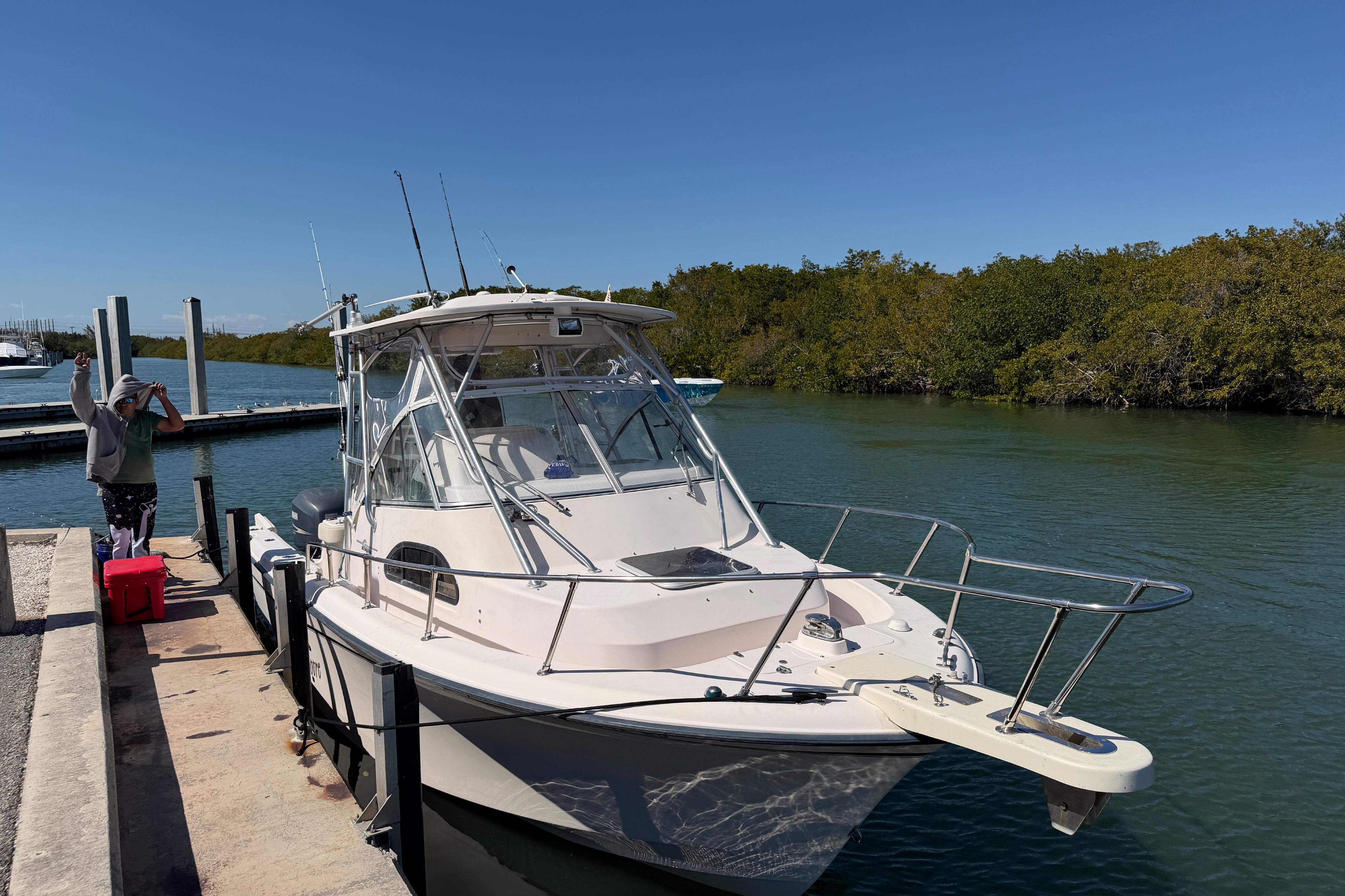 2006 Grady-White Sailfish 282 docked by a scenic waterway with lush greenery.