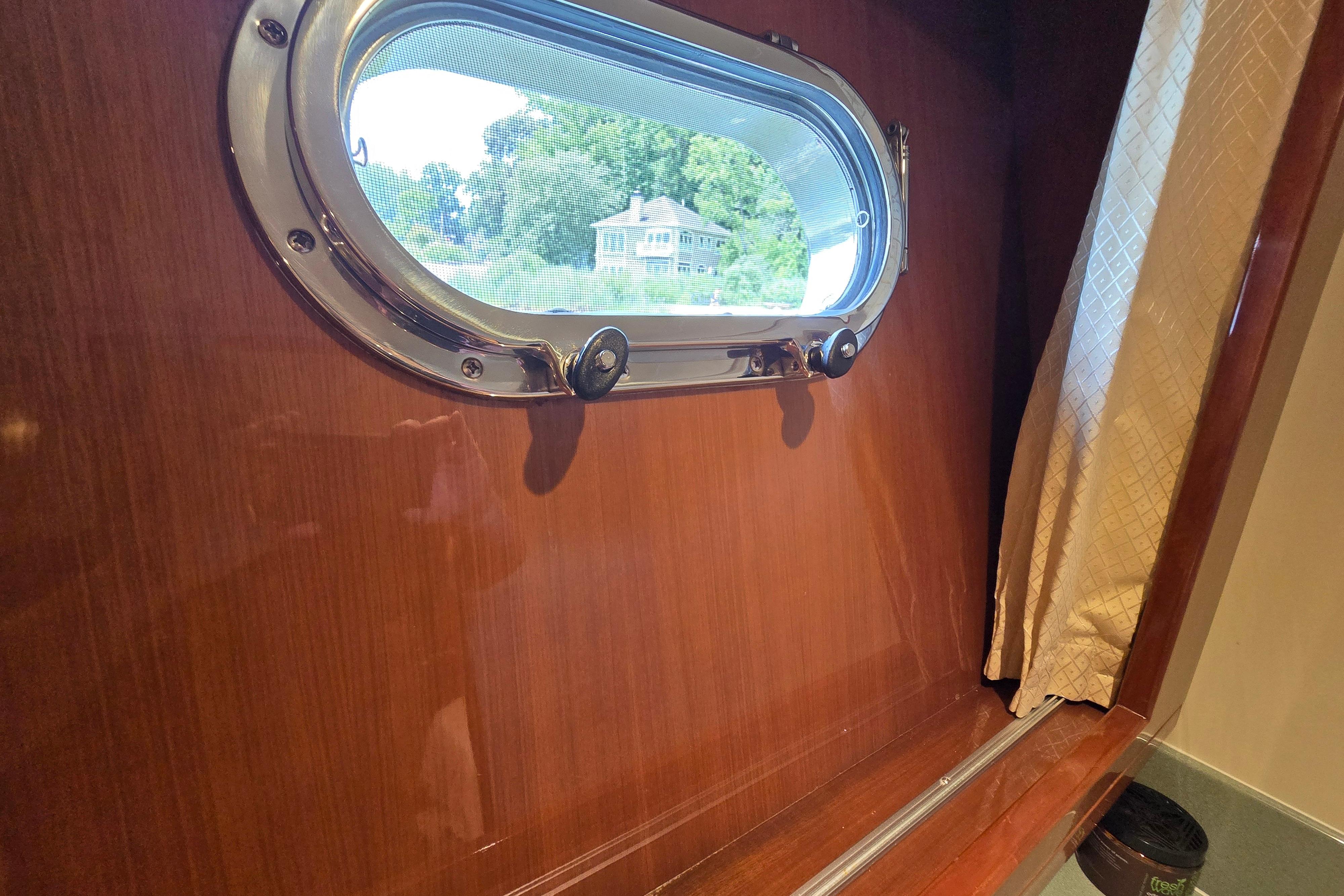 Porthole view from 2004 Grand Harbour 58 yacht, featuring wooden interior and curtain.