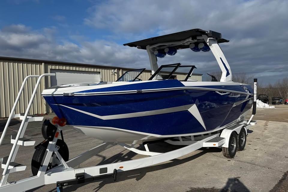 2026 Tigé Z3 boat in blue on a trailer, parked outdoors under cloudy skies.