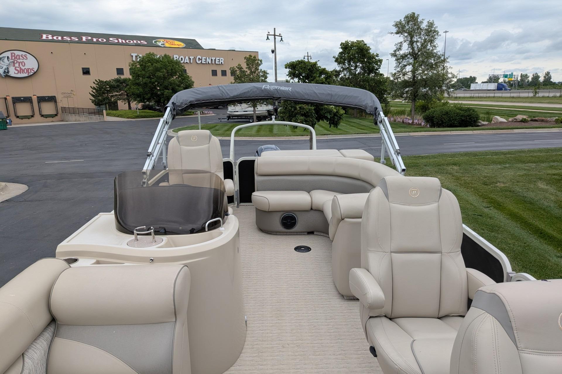 2018 Premier 220 SunSation pontoon boat at Bass Pro Shops, featuring beige seating and helm.
