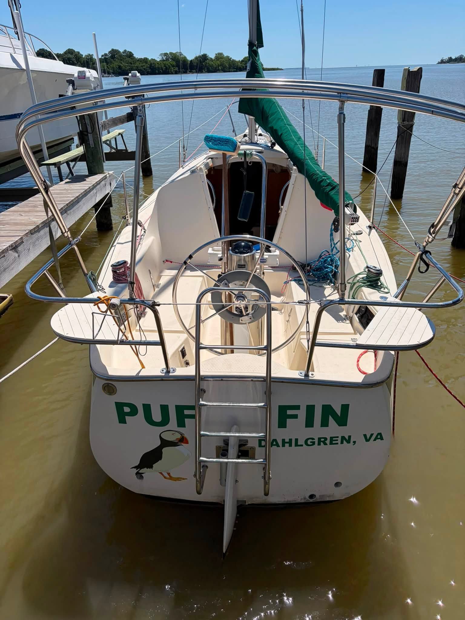 A sailboat named "Puffin" is docked. It features a green sail.