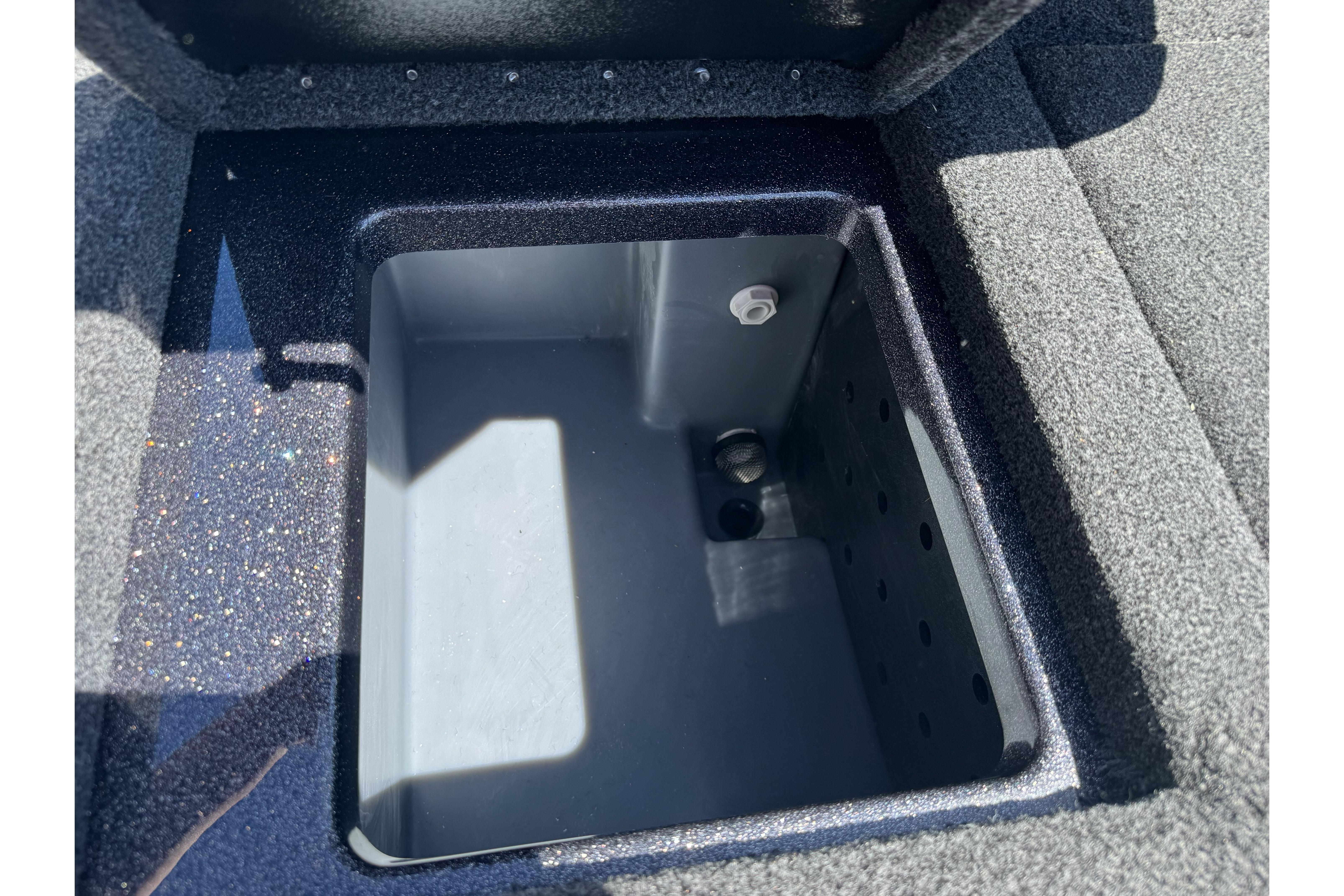 Open storage compartment in 2026 Triton 18 TrX boat, featuring a sleek, carpeted interior.