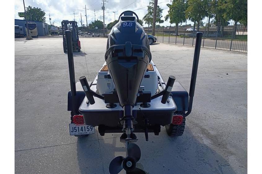 2013 Pelican Ambush boat with 9.8 HP motor on trailer, parked outdoors.