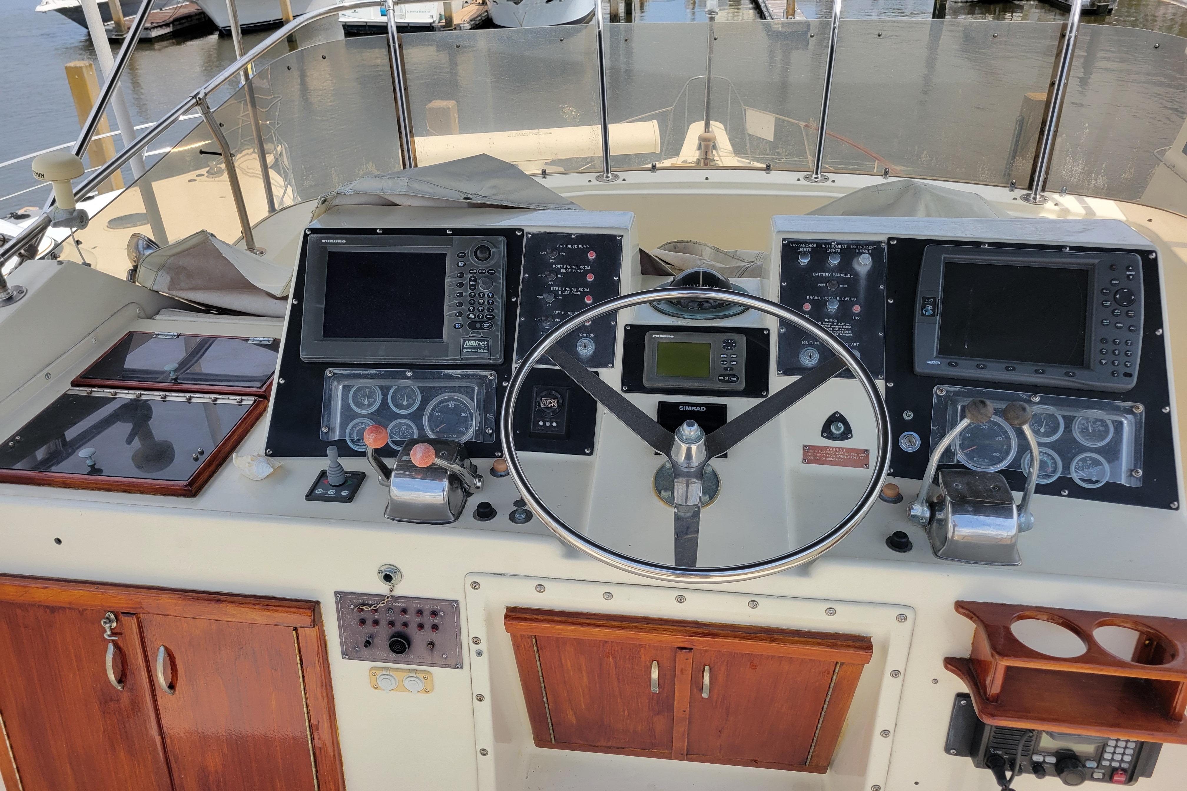 Helm of 1980 Hatteras 53 Yacht Fisherman with navigation equipment and wooden cabinetry.