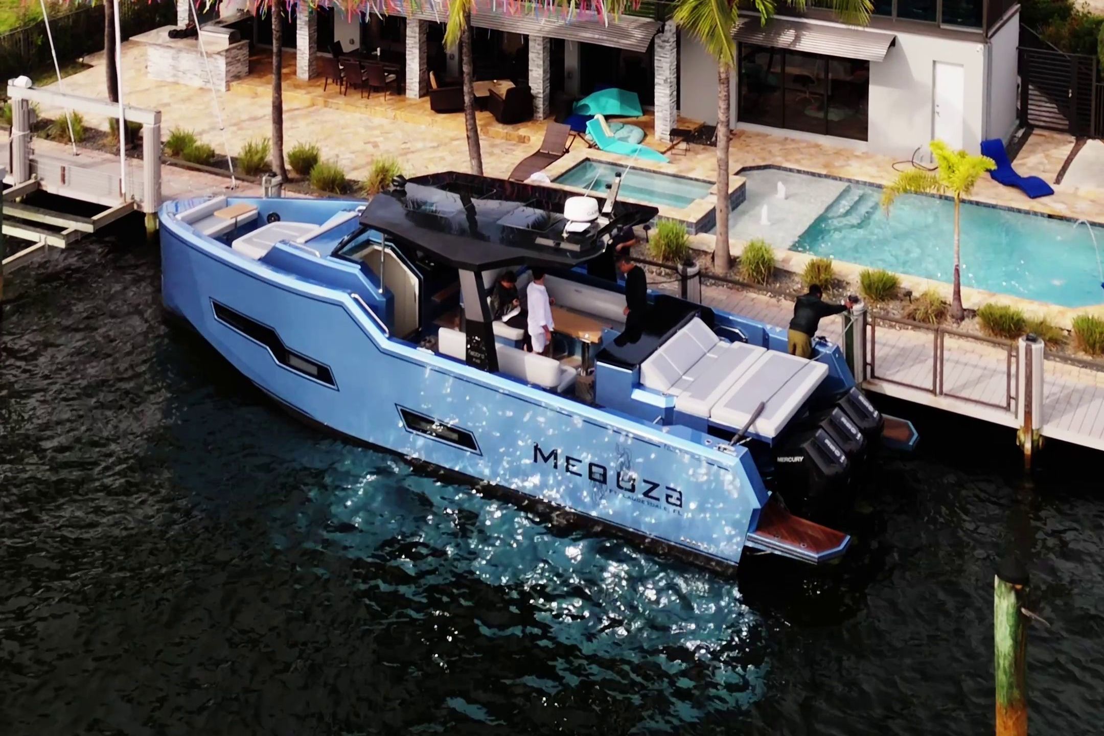 Fabbro F45 Cabrio Outboard 2025: Luxurious blue yacht docked with a pool and palm trees in the background.