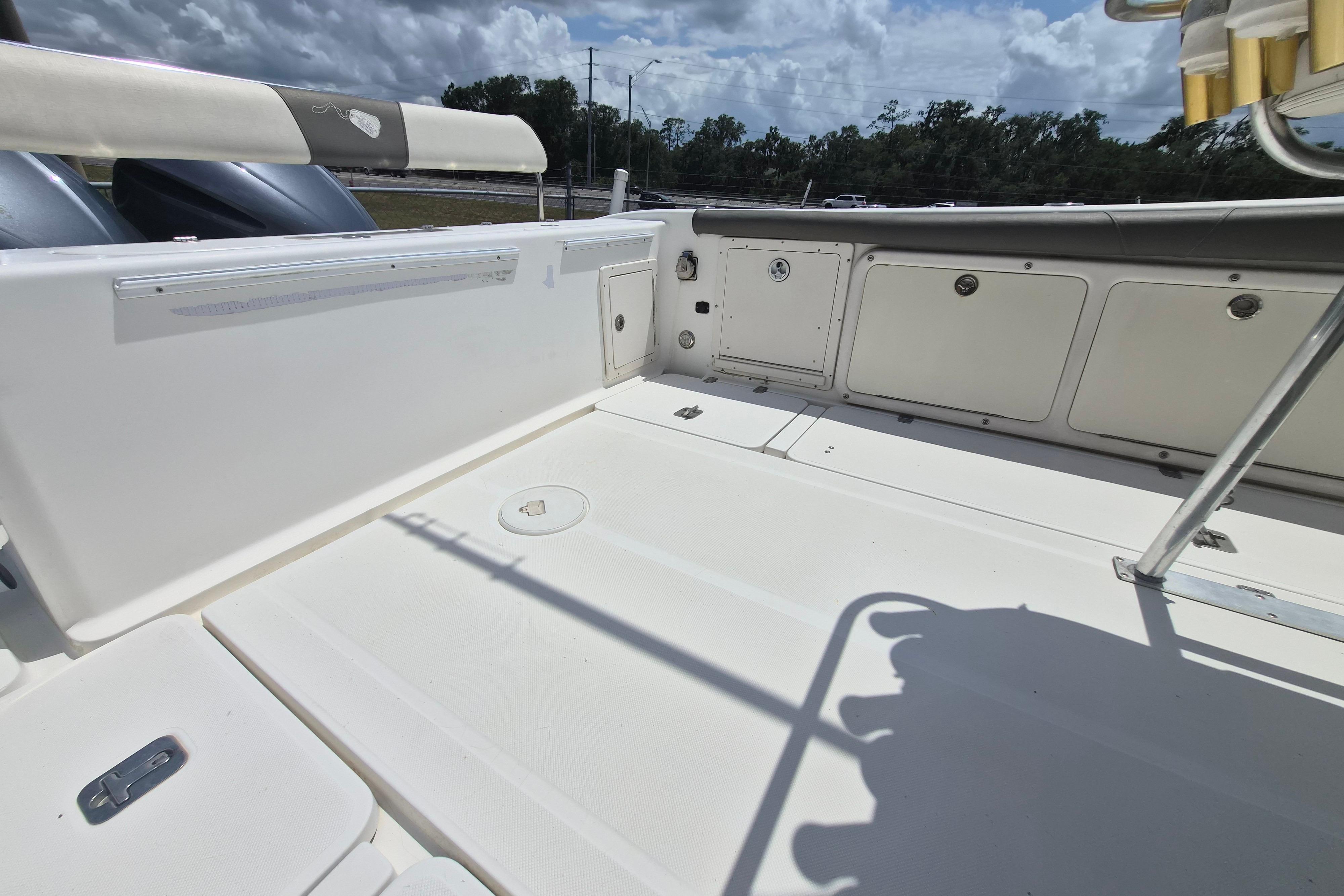 2006 Century 2900 Center Console boat deck with storage compartments under a cloudy sky.