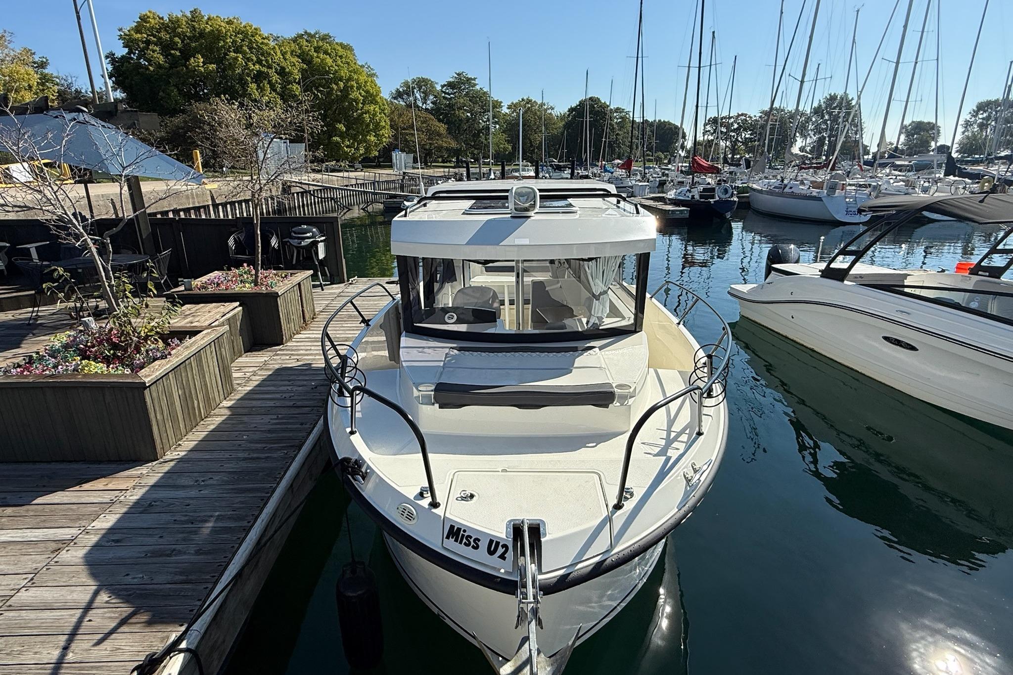 2024 Bayliner Trophy T25 Pilothouse docked at marina, surrounded by sailboats.