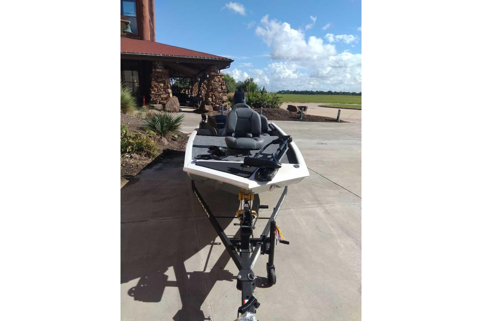 2026 Tracker Pro 170 boat on trailer, parked near a building under a clear blue sky.