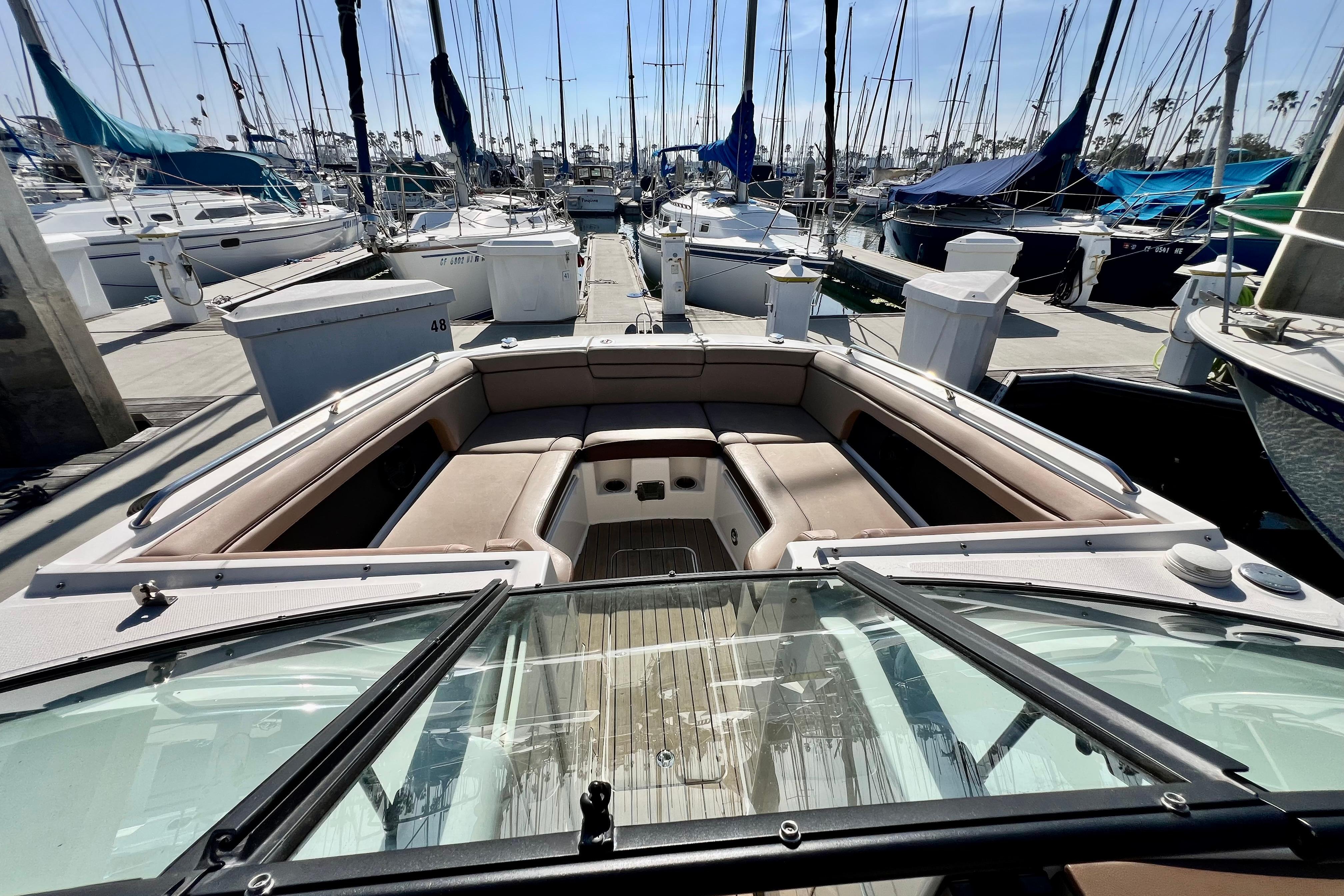 2016 Sea Ray 290 Sundeck Outboard boat docked at marina, surrounded by sailboats.