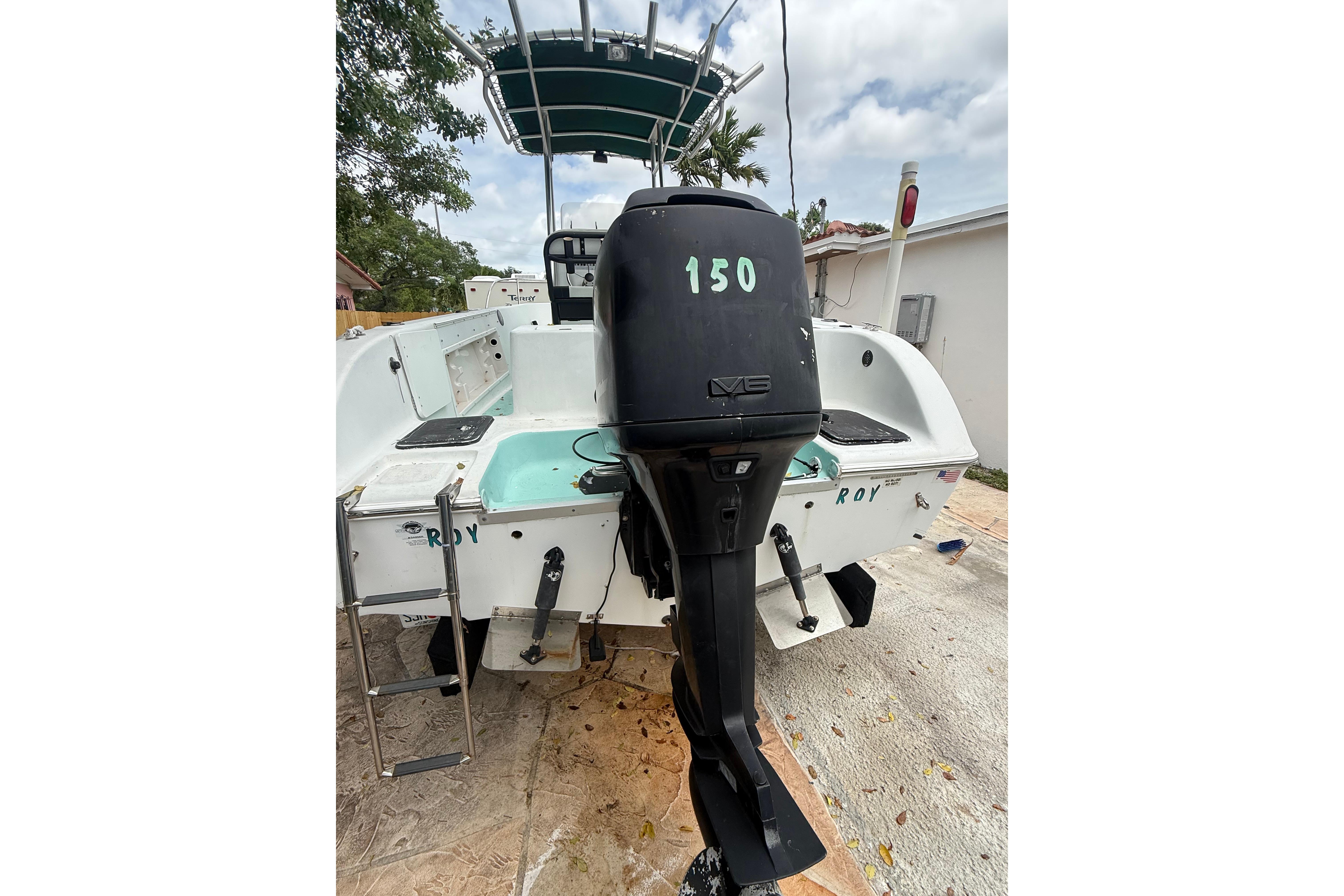 2005 LYG Sea Fox boat with outboard motor and ladder, parked outdoors.