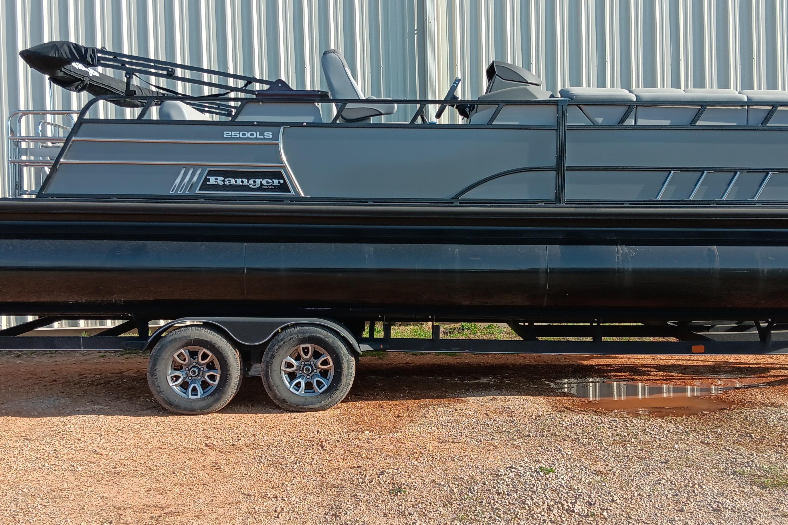 2023 Ranger 2500LS pontoon boat on trailer, parked on gravel near metal building.